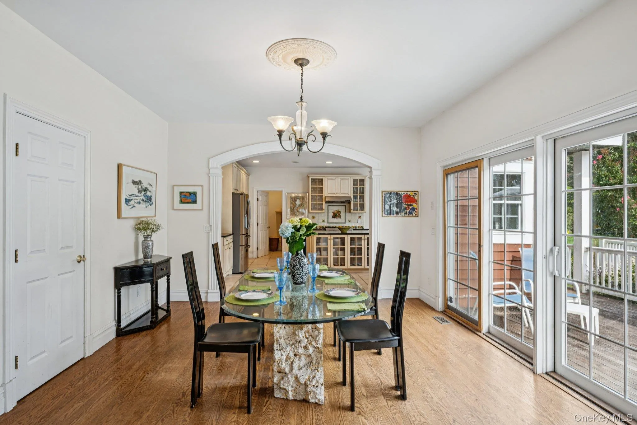 Sophisticated dining area adorned with arched walkways, rich wood-finished floors, and a statement chandelier. Sophisticated dining area adorned with arched walkways, rich wood-finished floors, and a statement chandelier.