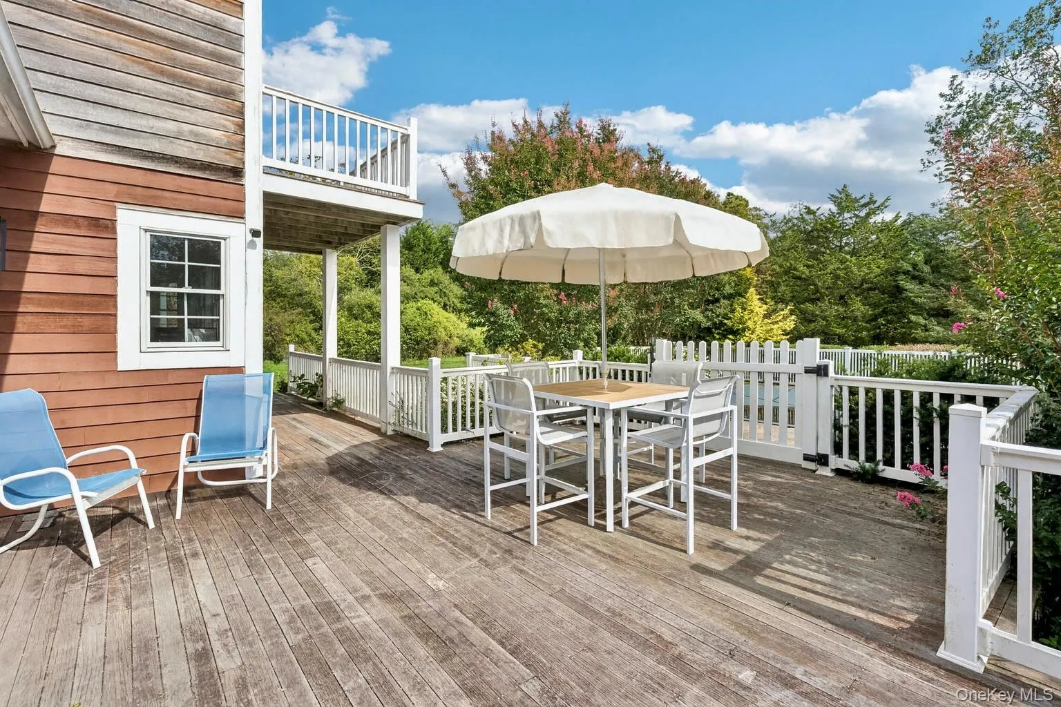 Expansive mahogany deck featuring an inviting outdoor dining area with seamless access through sliding glass door. Expansive mahogany deck featuring an inviting outdoor dining area with seamless access through sliding glass door.