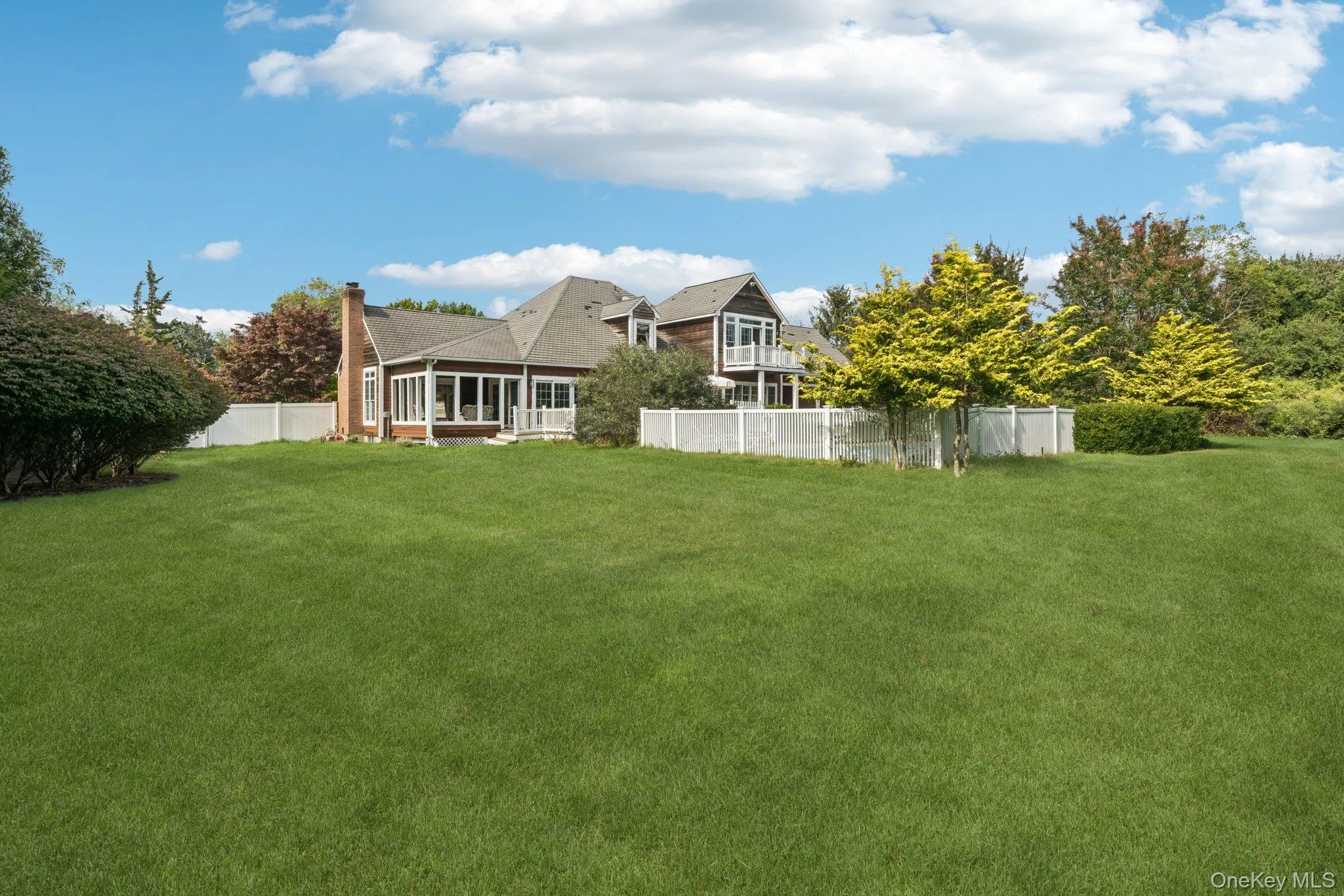 Rear elevation showcasing the home’s fenced backyard, classic chimney, and inviting sunroom. Rear elevation showcasing the home’s fenced backyard, classic chimney, and inviting sunroom.