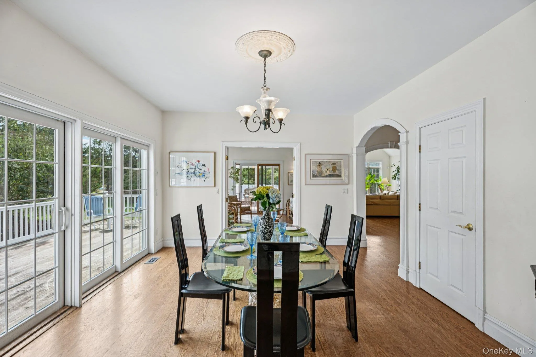 An inviting dining area showcasing graceful arched walkways, warm wood-finished floors, and a stunning chandelier that anchors the space with timeless elegance. An inviting dining area showcasing graceful arched walkways, warm wood-finished floors, and a stunning chandelier that anchors the space with timeless elegance.