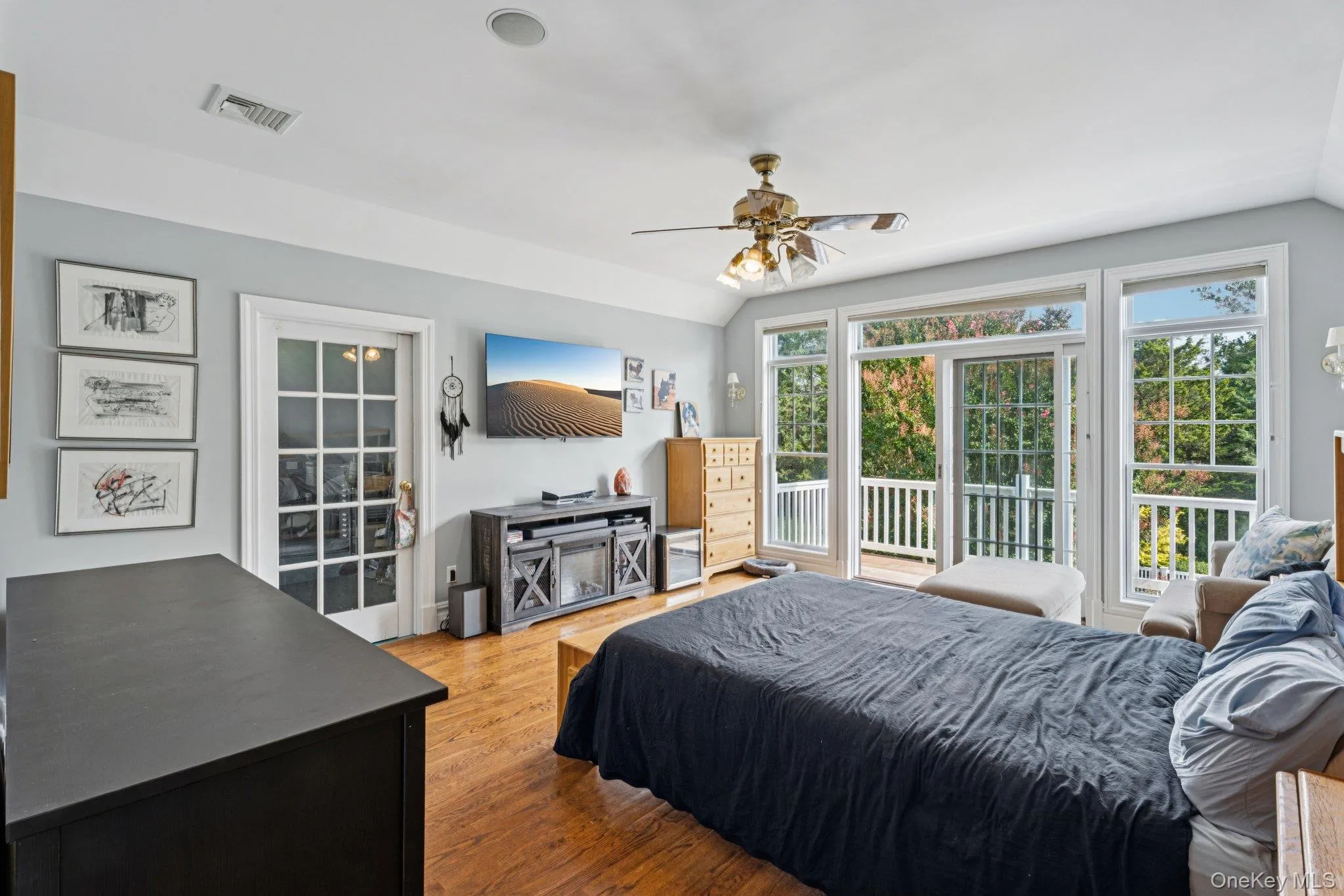 An inviting primary bedroom adorned with wood-finished floors and vaulted ceilings, complete with a ceiling fan and private access to the outdoors. An inviting primary bedroom adorned with wood-finished floors and vaulted ceilings, complete with a ceiling fan and private access to the outdoors.