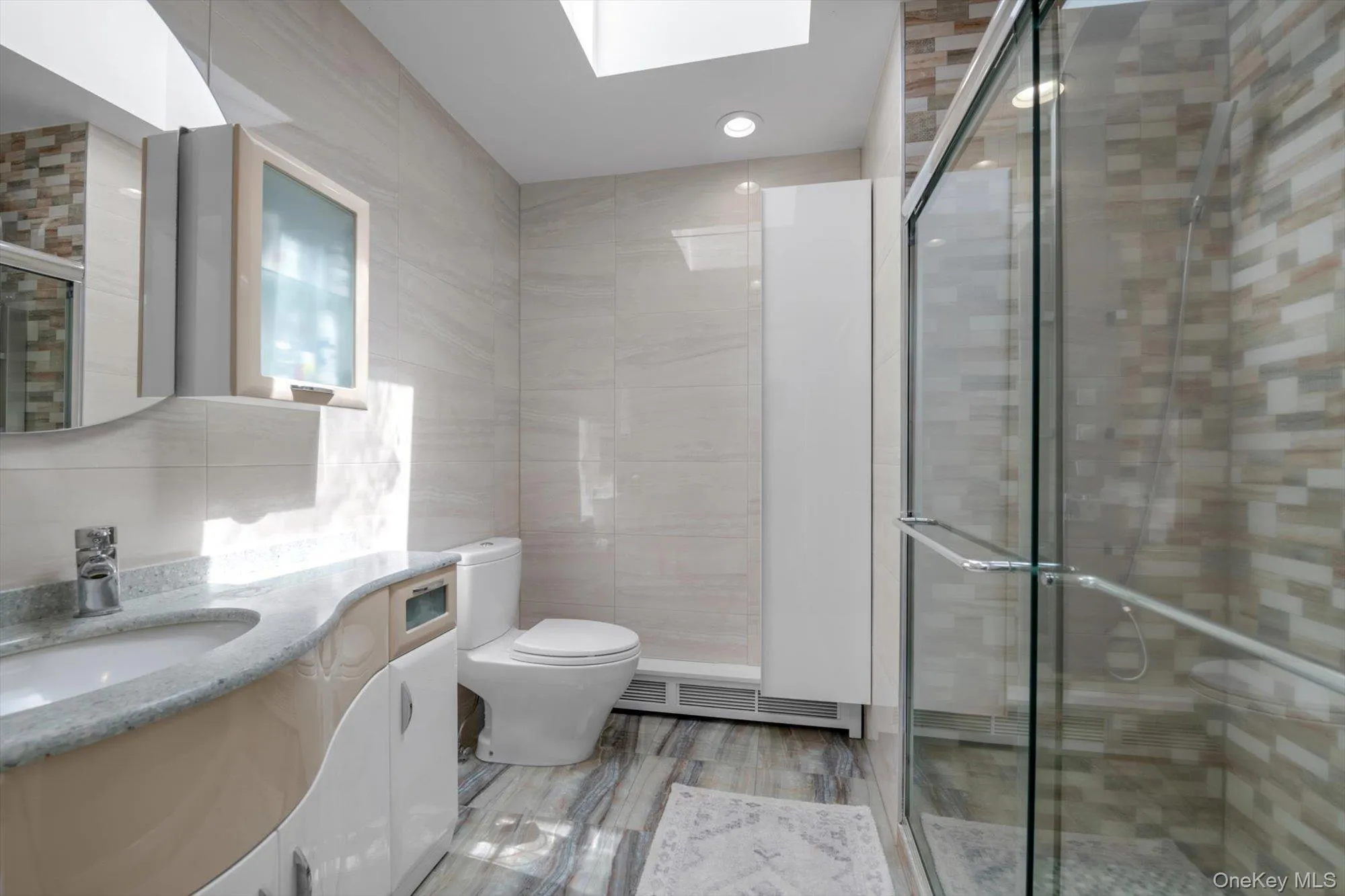 Full bath with tile walls, a skylight, vanity, and a stall shower Full bath with tile walls, a skylight, vanity, and a stall shower