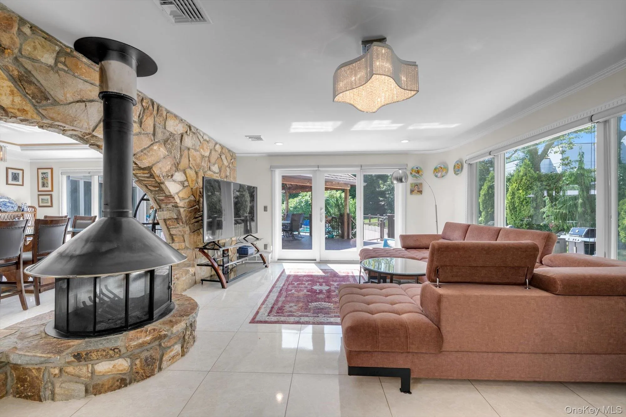 Family room featuring ornamental molding, healthy amount of natural light, light tile patterned floors, and a wood burning fireplace Family room featuring ornamental molding, healthy amount of natural light, light tile patterned floors, and a wood burning fireplace