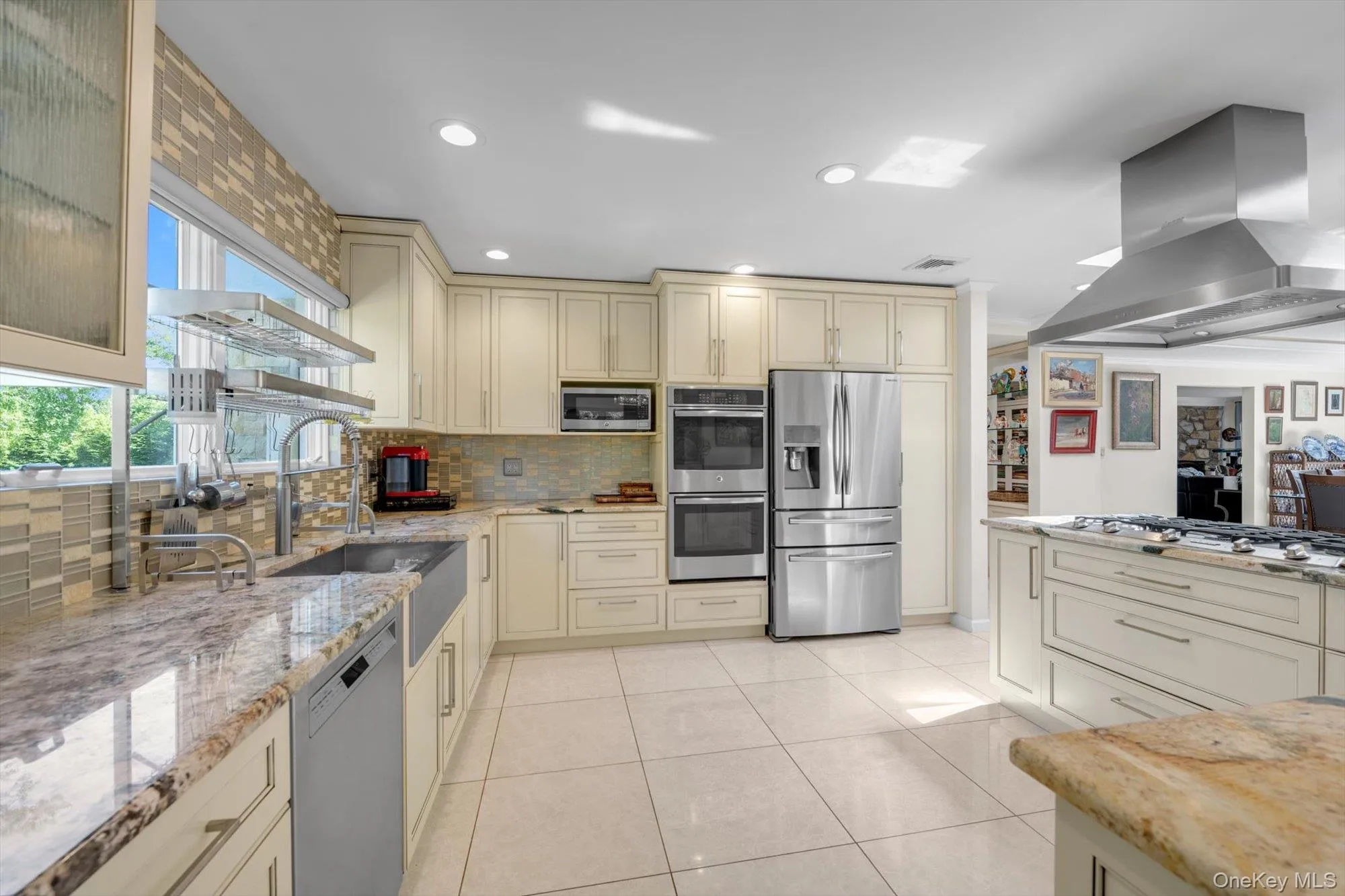 Kitchen featuring Wood cabinets, wall chimney range hood, stainless steel appliances, backsplash, and island with seating Kitchen featuring Wood cabinets, wall chimney range hood, stainless steel appliances, backsplash, and island with seating