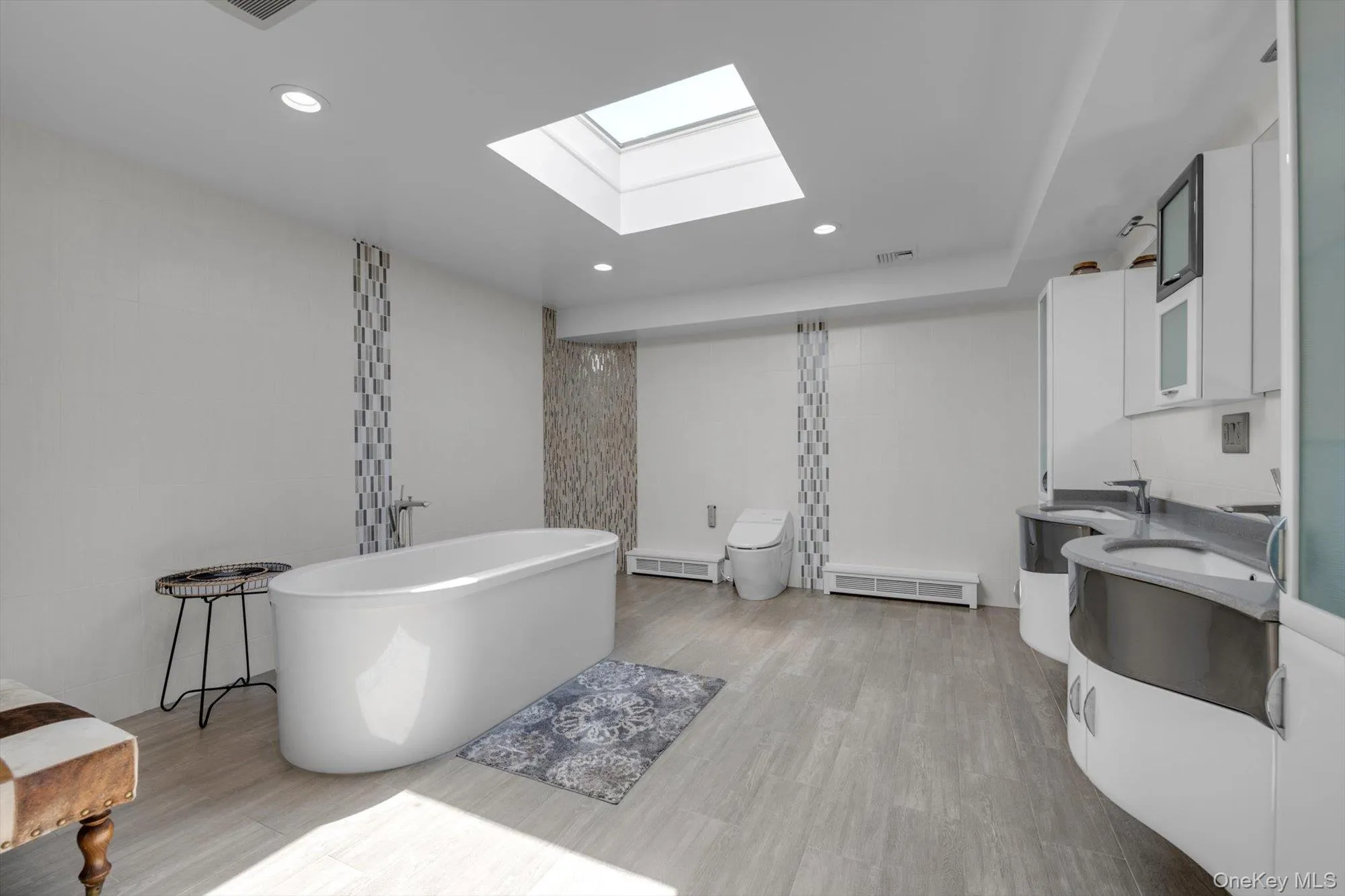 Primary Bathroom with a freestanding tub, vanity, a skylight, recessed lighting, and wood finished floors Primary Bathroom with a freestanding tub, vanity, a skylight, recessed lighting, and wood finished floors