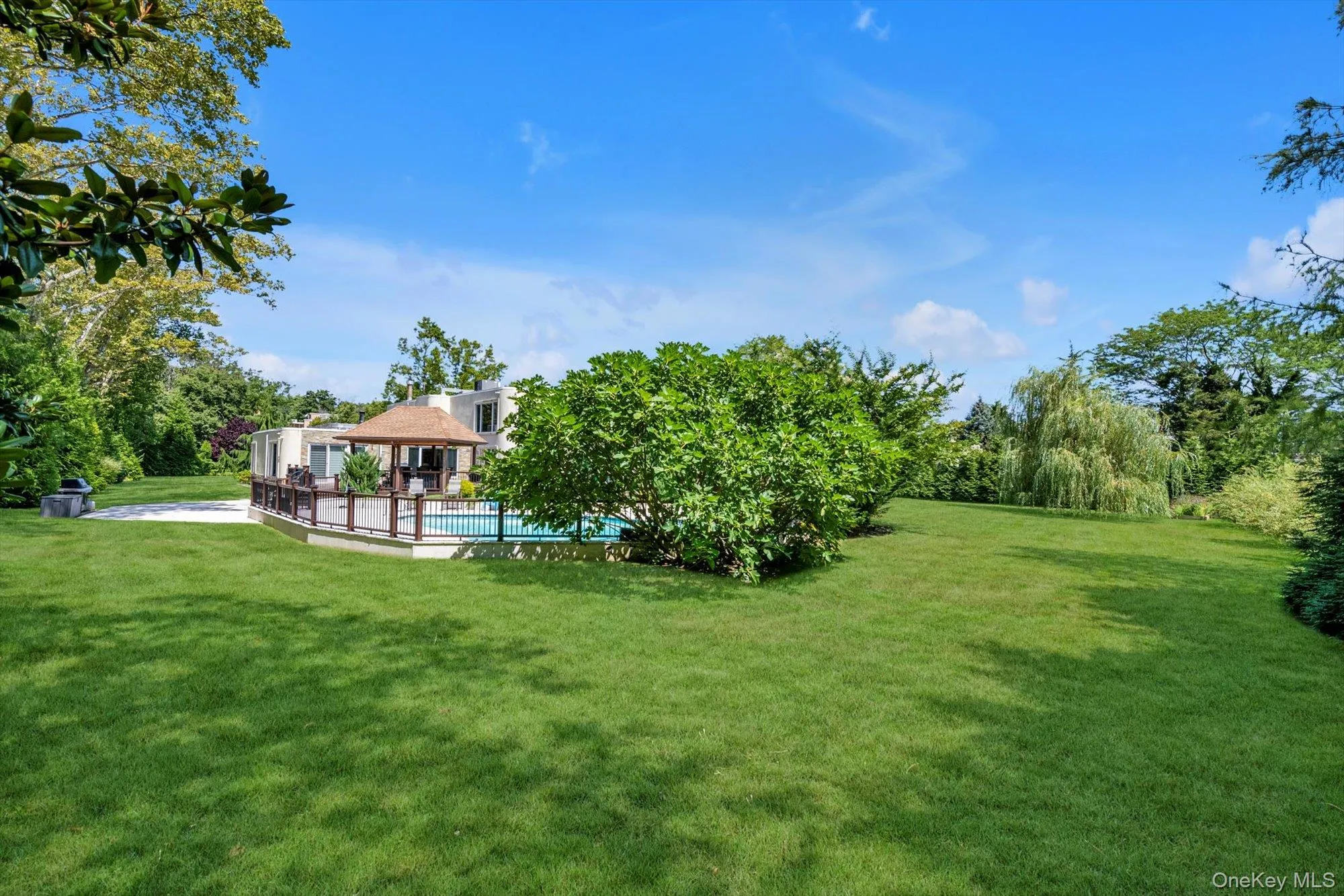 View of grassy yard featuring an outdoor pool, a gazebo, and view of scattered trees View of grassy yard featuring an outdoor pool, a gazebo, and view of scattered trees