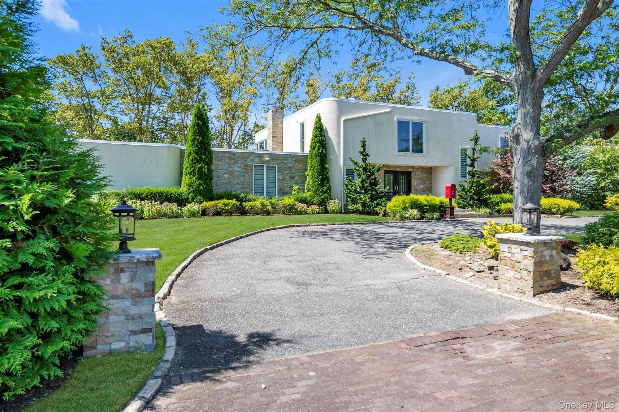 View of front of home with circular driveway, stucco siding, a front yard, stone siding, and a chimney View of front of home with circular driveway, stucco siding, a front yard, stone siding, and a chimney