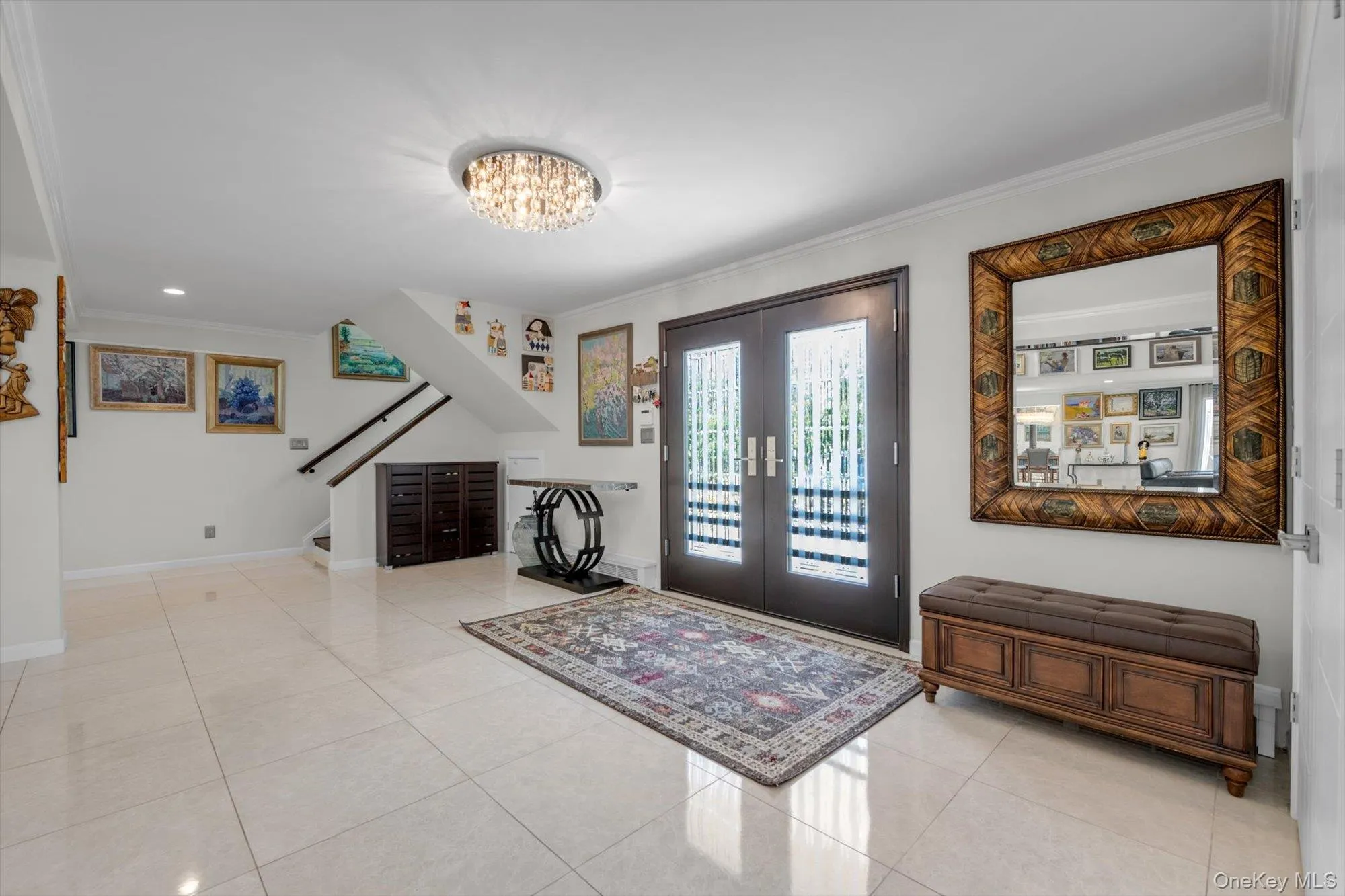 Entrance foyer with crown molding, french doors, light tile patterned floors, and a chandelier Entrance foyer with crown molding, french doors, light tile patterned floors, and a chandelier