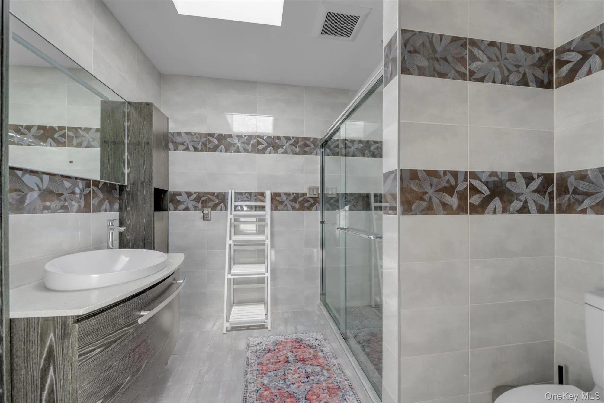 Bathroom featuring tile walls, a stall shower, vanity, and tile patterned flooring Bathroom featuring tile walls, a stall shower, vanity, and tile patterned flooring