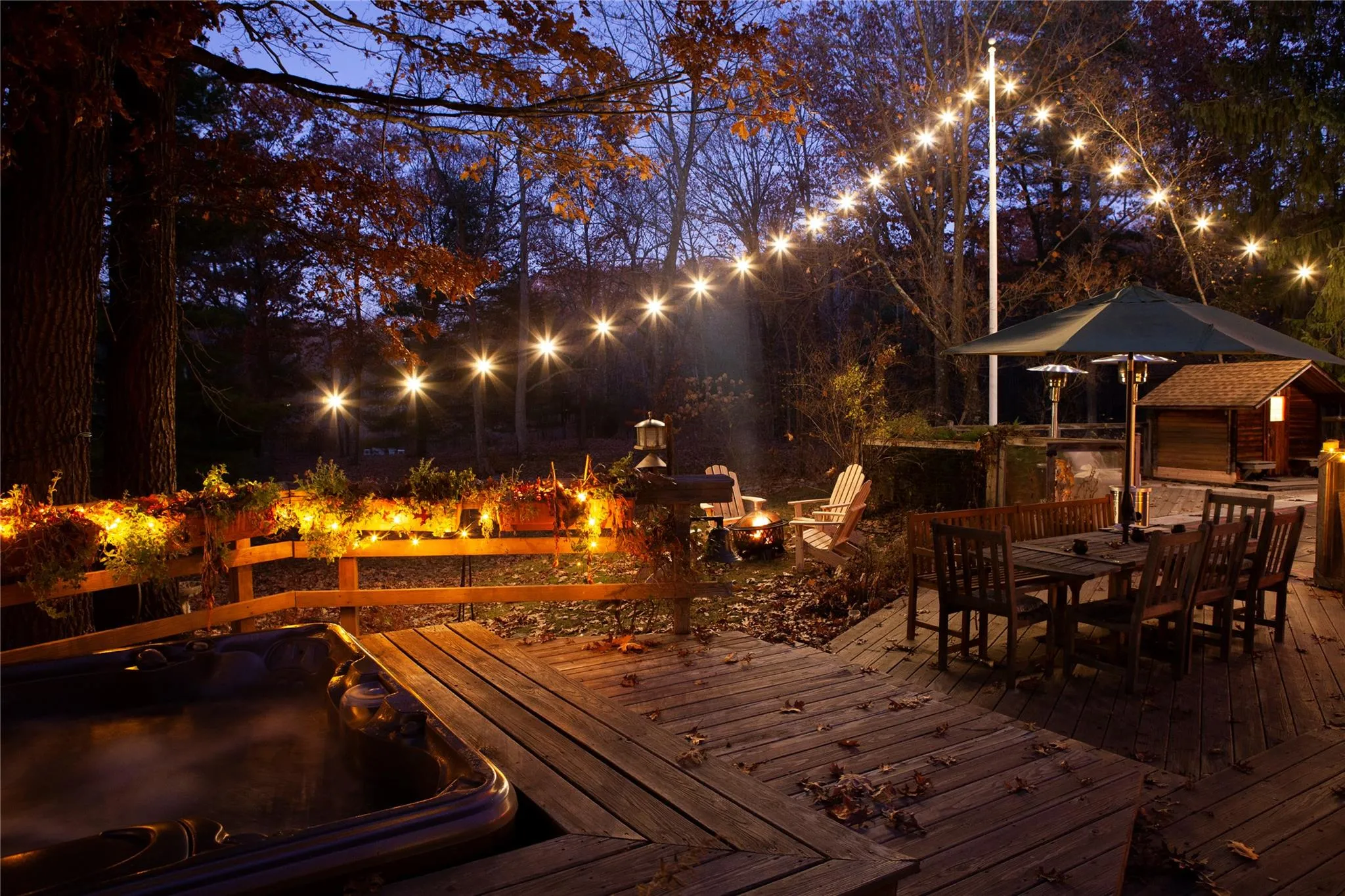 Deck at night featuring a fire pit, an outdoor structure, and outdoor dining area Deck at night featuring a fire pit, an outdoor structure, and outdoor dining area