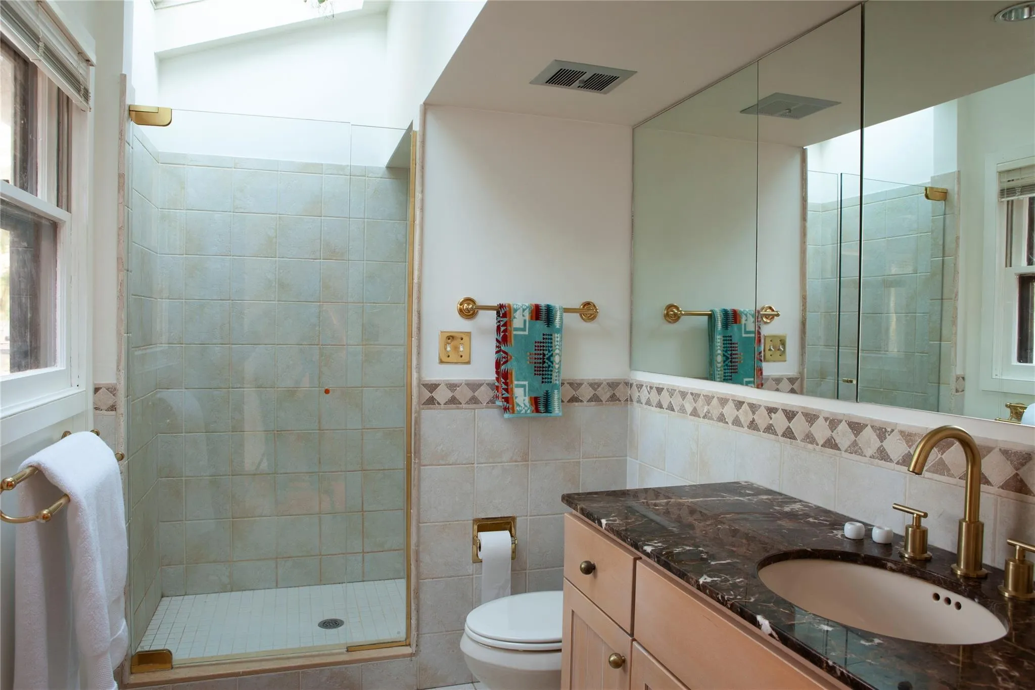 Bathroom with vanity, tile walls, a shower stall, and wainscoting Bathroom with vanity, tile walls, a shower stall, and wainscoting