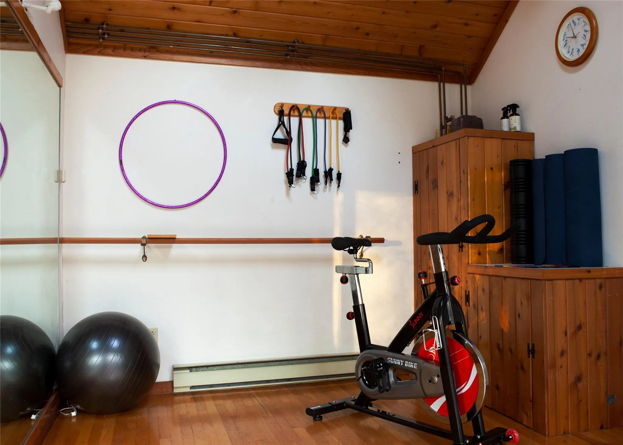 Workout area featuring a baseboard heating unit, wood finished floors, and wood ceiling Workout area featuring a baseboard heating unit, wood finished floors, and wood ceiling