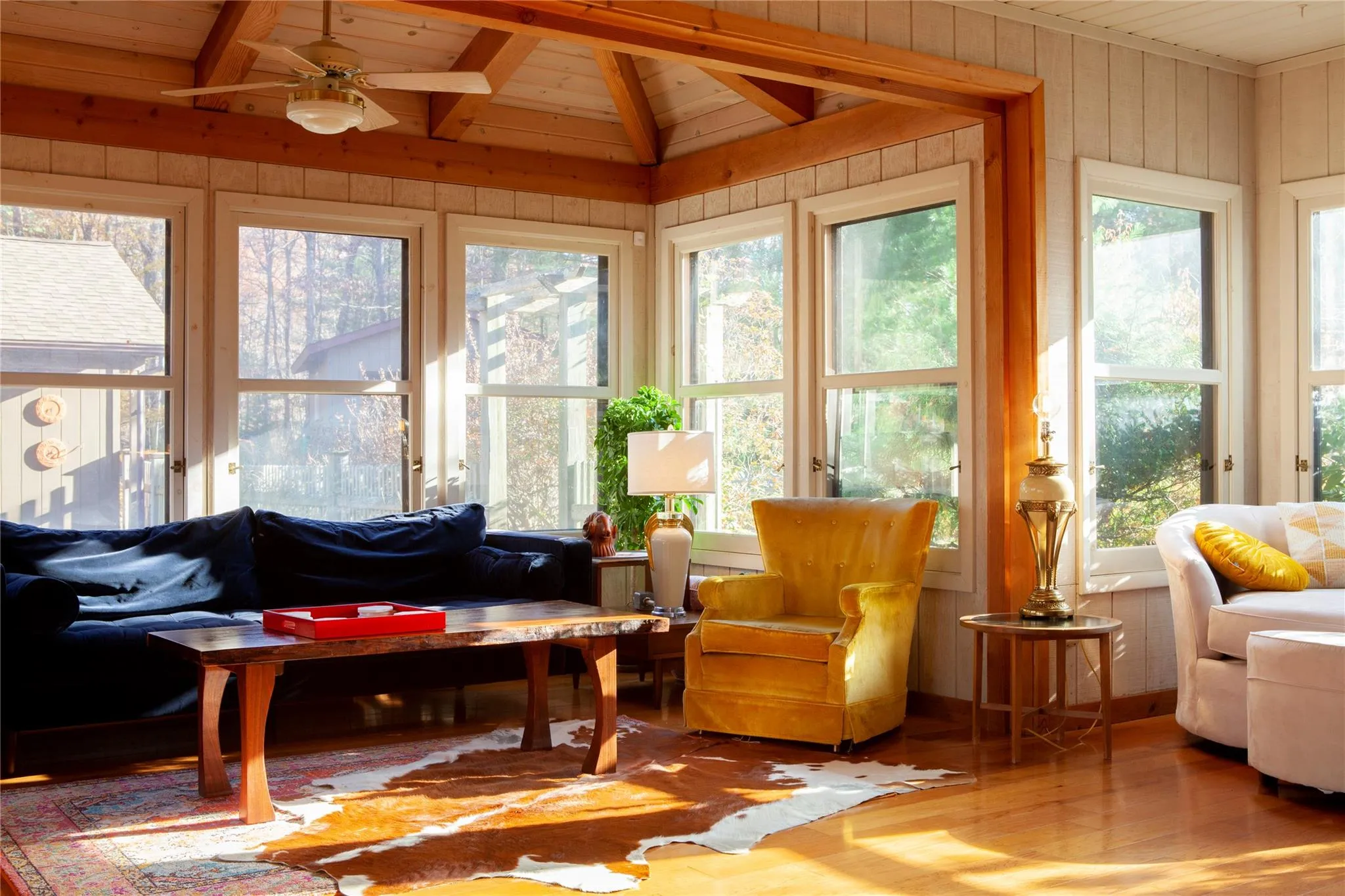 Sunroom with wood finished floors, a wooden ceiling with exposed beams, and wooden walls Sunroom with wood finished floors, a wooden ceiling with exposed beams, and wooden walls