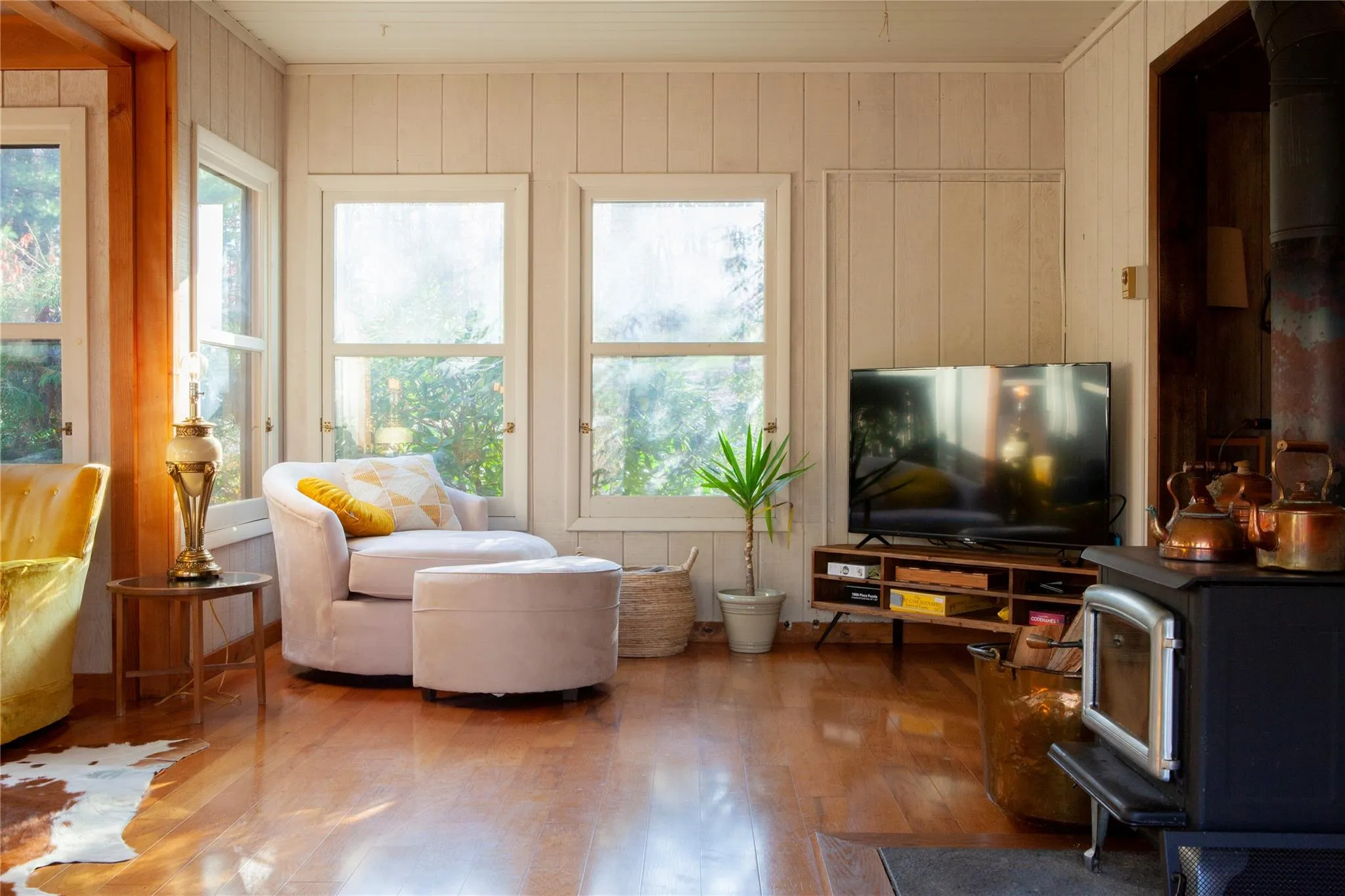Living room featuring a wood stove, hardwood / wood-style flooring, wood walls, and crown molding Living room featuring a wood stove, hardwood / wood-style flooring, wood walls, and crown molding