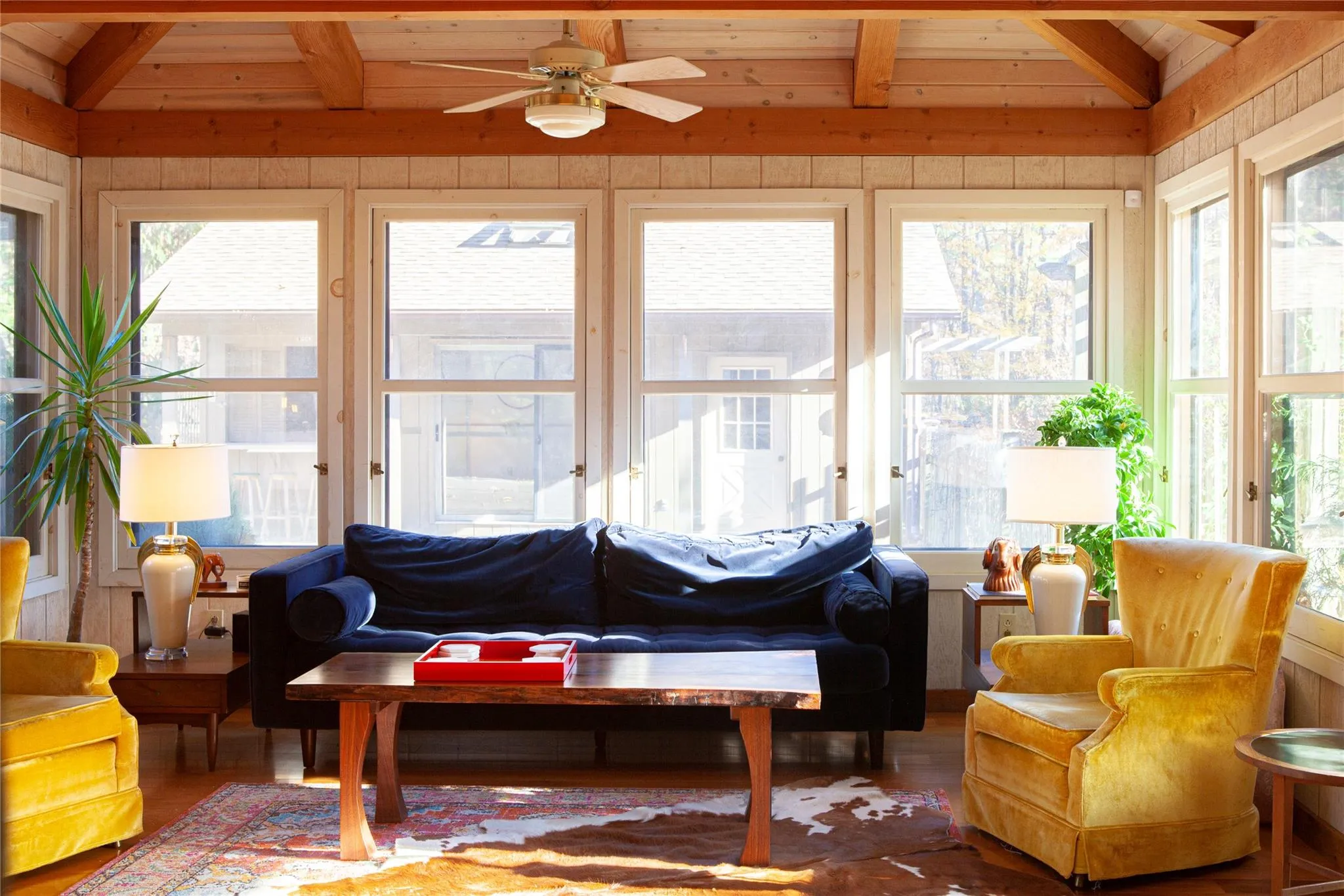 Sunroom featuring beamed ceiling, wood finished floors, and wooden walls Sunroom featuring beamed ceiling, wood finished floors, and wooden walls