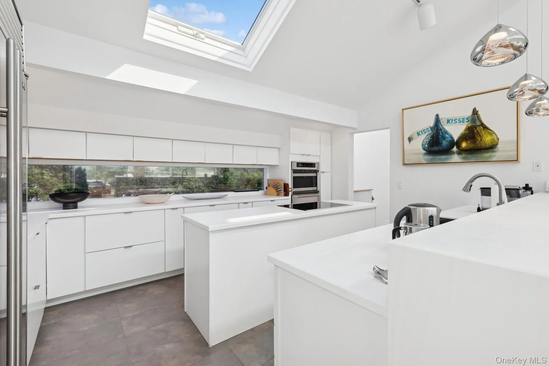 Kitchen featuring a kitchen island, modern cabinets, white cabinetry, a skylight, and light countertops Kitchen featuring a kitchen island, modern cabinets, white cabinetry, a skylight, and light countertops