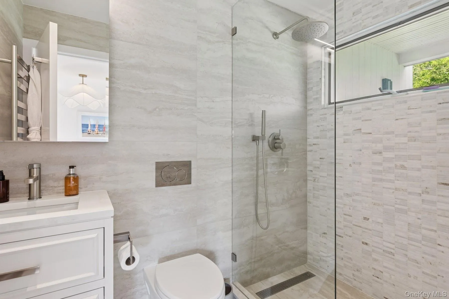 Full bathroom featuring a stall shower, vanity, tile walls, and a towel warmer Full bathroom featuring a stall shower, vanity, tile walls, and a towel warmer