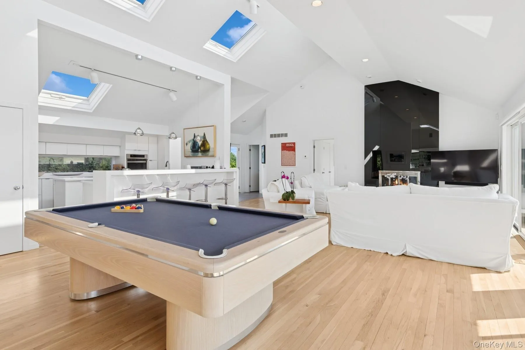 Game room with a skylight, high vaulted ceiling, billiards table, rail lighting, and light wood-type flooring Game room with a skylight, high vaulted ceiling, billiards table, rail lighting, and light wood-type flooring
