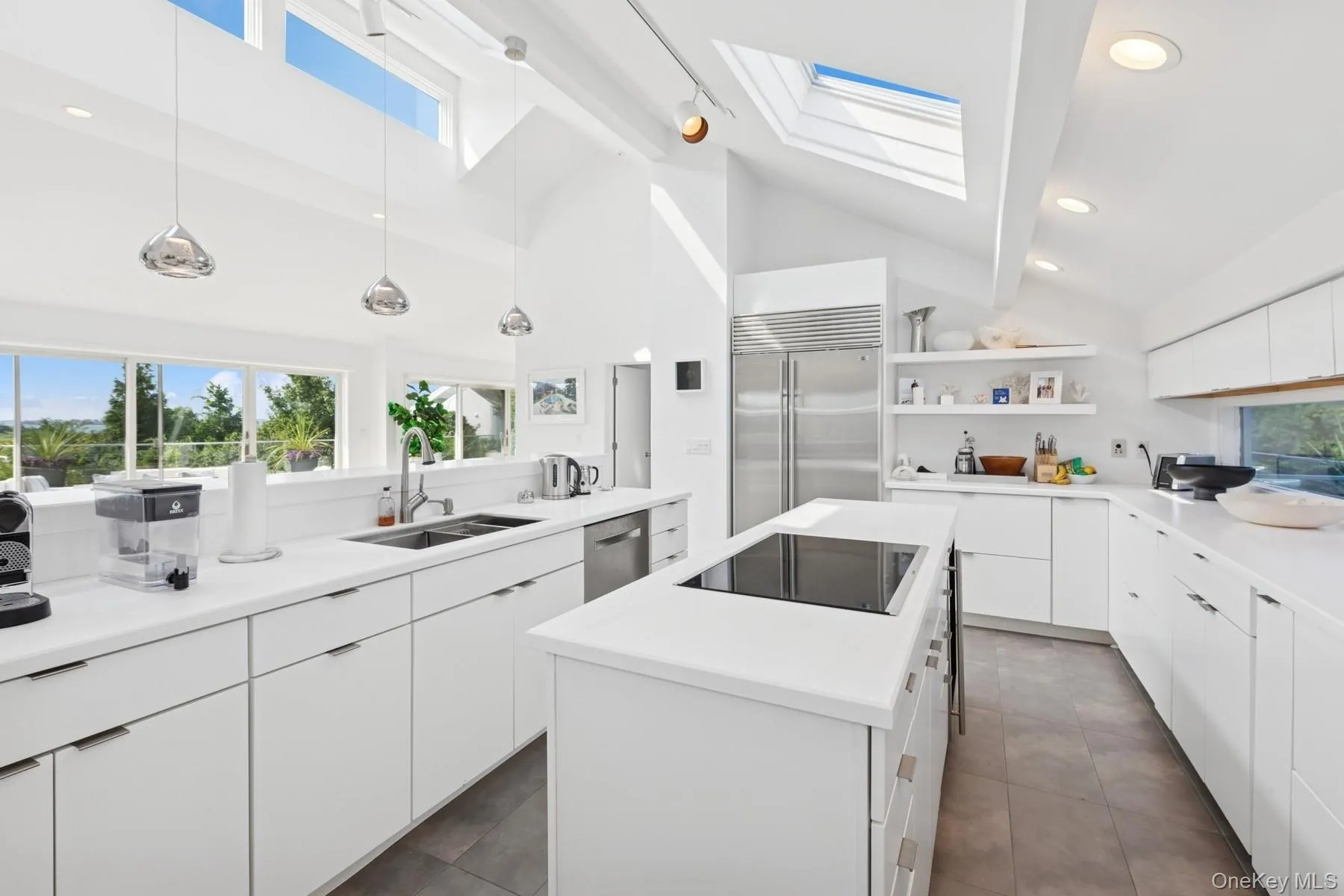 Kitchen featuring a skylight, open shelves, a center island, white cabinets, and appliances with stainless steel finishes Kitchen featuring a skylight, open shelves, a center island, white cabinets, and appliances with stainless steel finishes