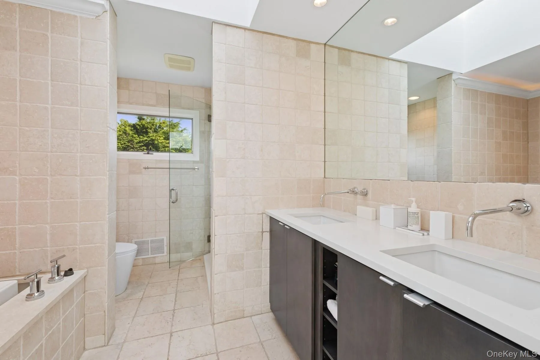 Bathroom featuring tile walls, a stall shower, double vanity, recessed lighting, and tile patterned floors Bathroom featuring tile walls, a stall shower, double vanity, recessed lighting, and tile patterned floors