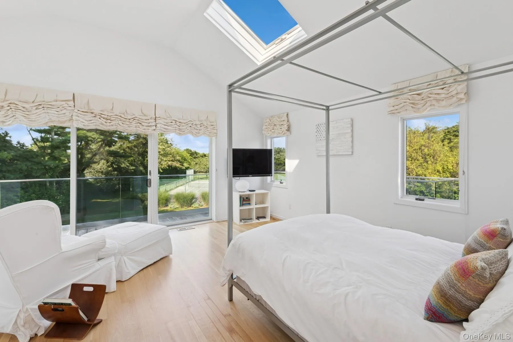 Bedroom featuring a skylight, wood finished floors, lofted ceiling, and access to outside Bedroom featuring a skylight, wood finished floors, lofted ceiling, and access to outside