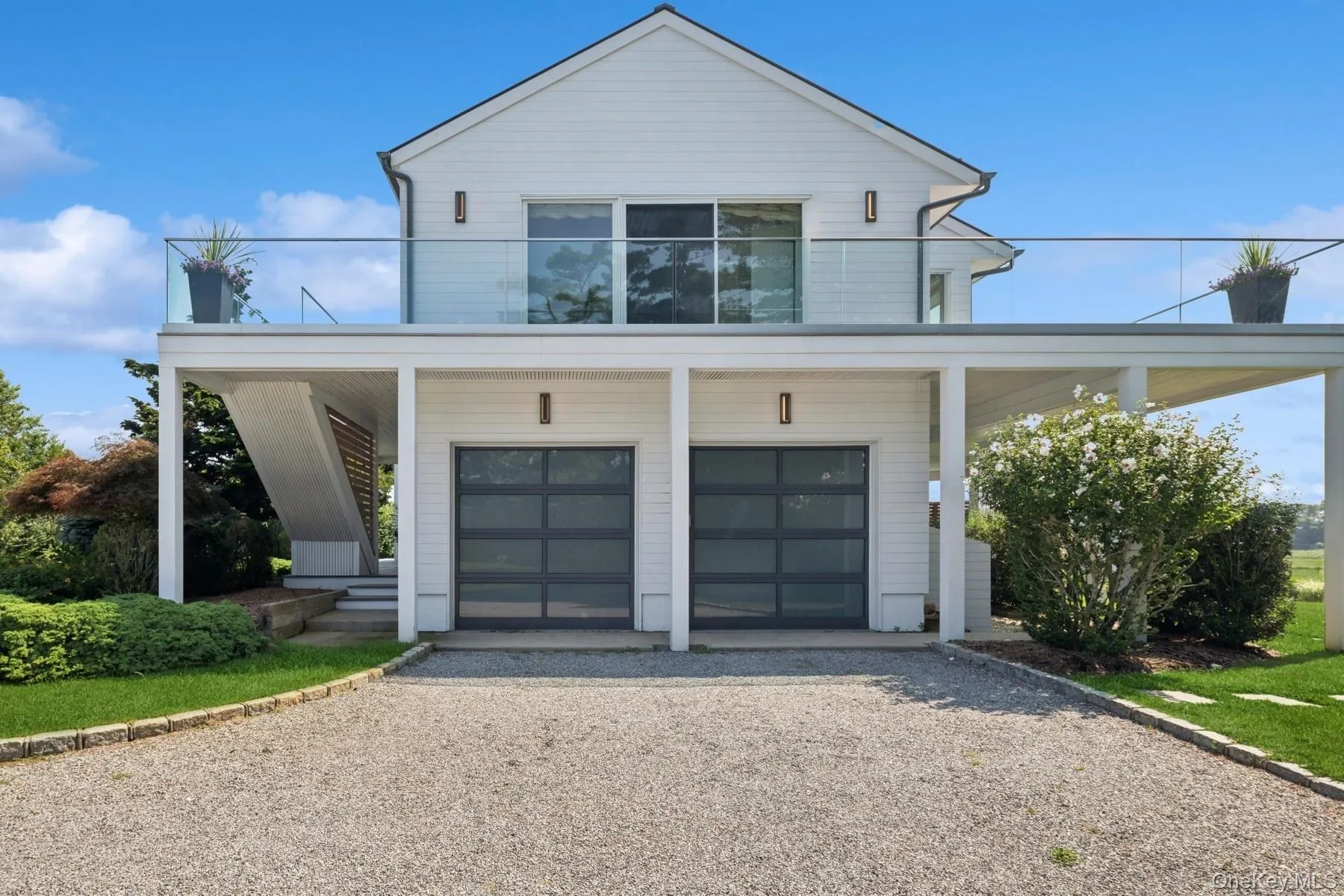 Modern home featuring gravel driveway, a garage, and covered porch Modern home featuring gravel driveway, a garage, and covered porch