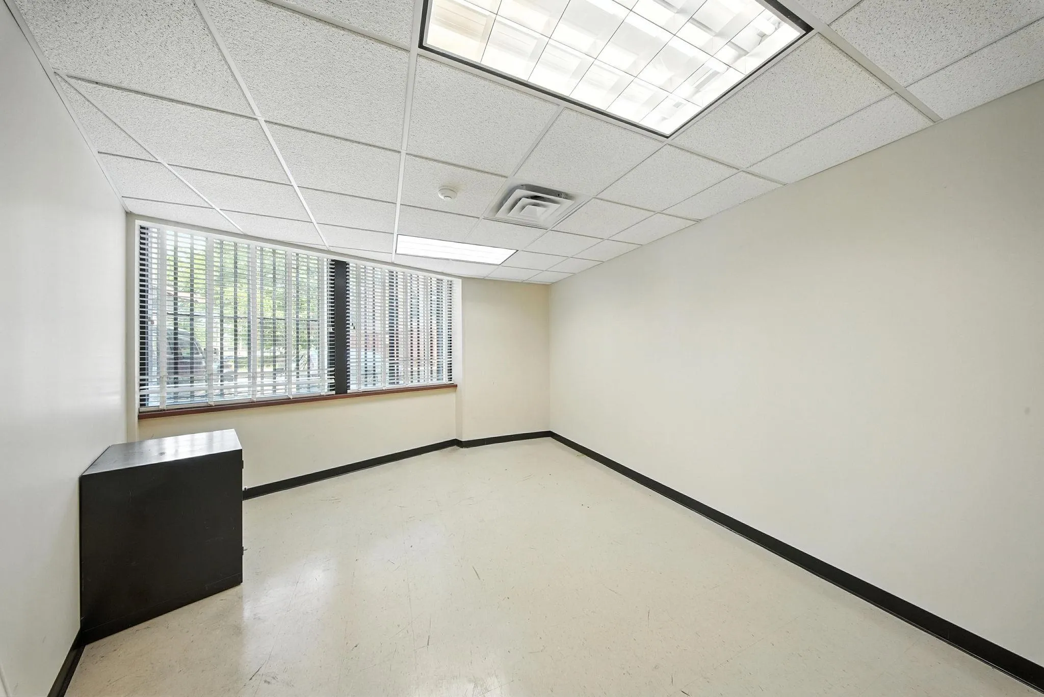 Unfurnished room with a paneled ceiling and concrete flooring Unfurnished room with a paneled ceiling and concrete flooring