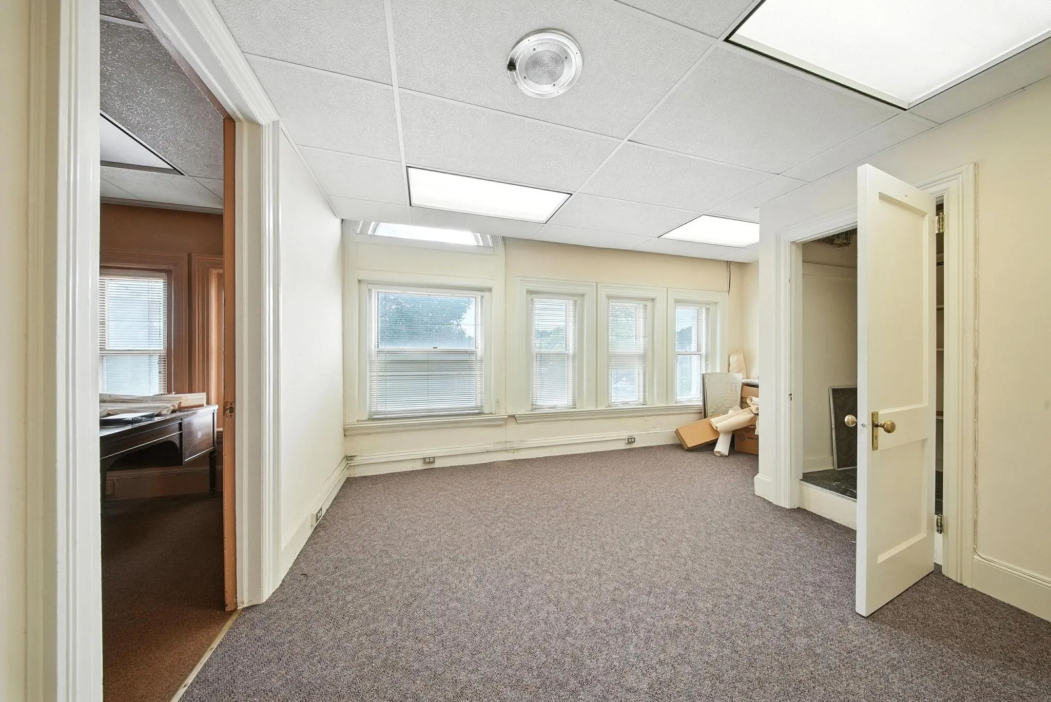 Hallway featuring a paneled ceiling, carpet floors, and healthy amount of natural light Hallway featuring a paneled ceiling, carpet floors, and healthy amount of natural light