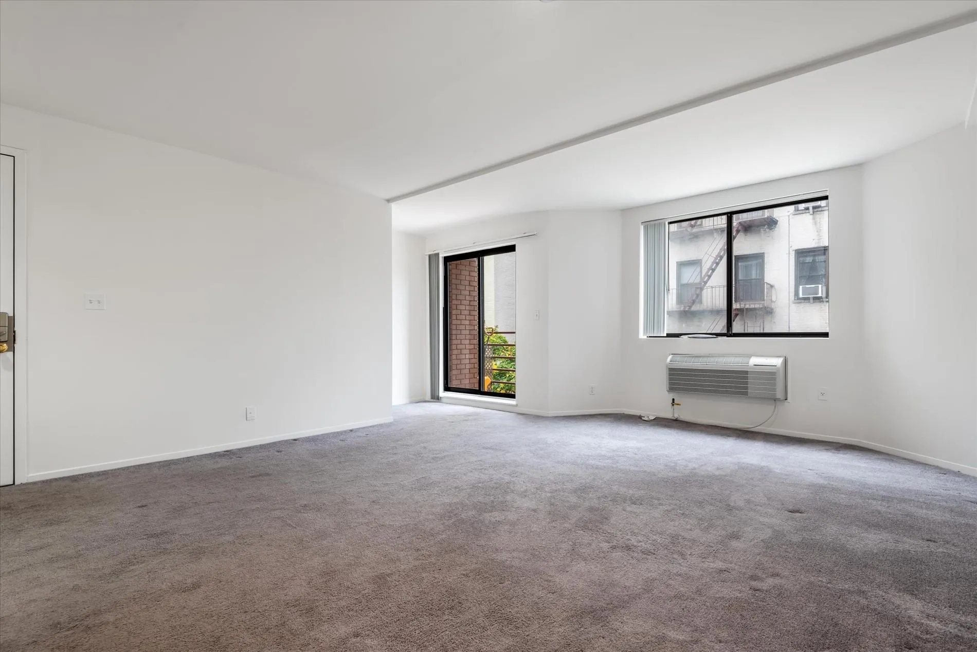Spare room with healthy amount of natural light, carpet floors, and an AC wall unit Spare room with healthy amount of natural light, carpet floors, and an AC wall unit