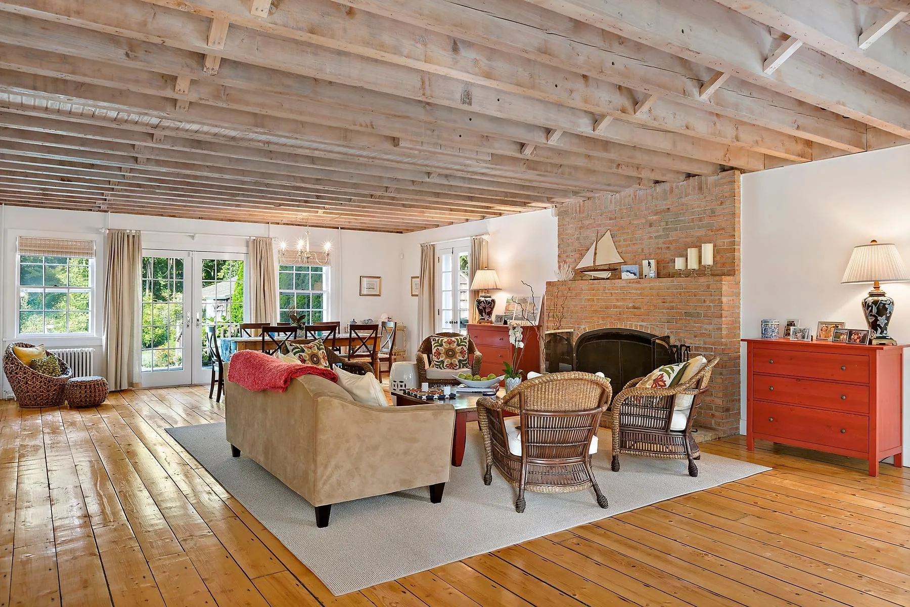 Living area featuring hardwood / wood-style flooring, a chandelier, a brick fireplace, and french doors Living area featuring hardwood / wood-style flooring, a chandelier, a brick fireplace, and french doors