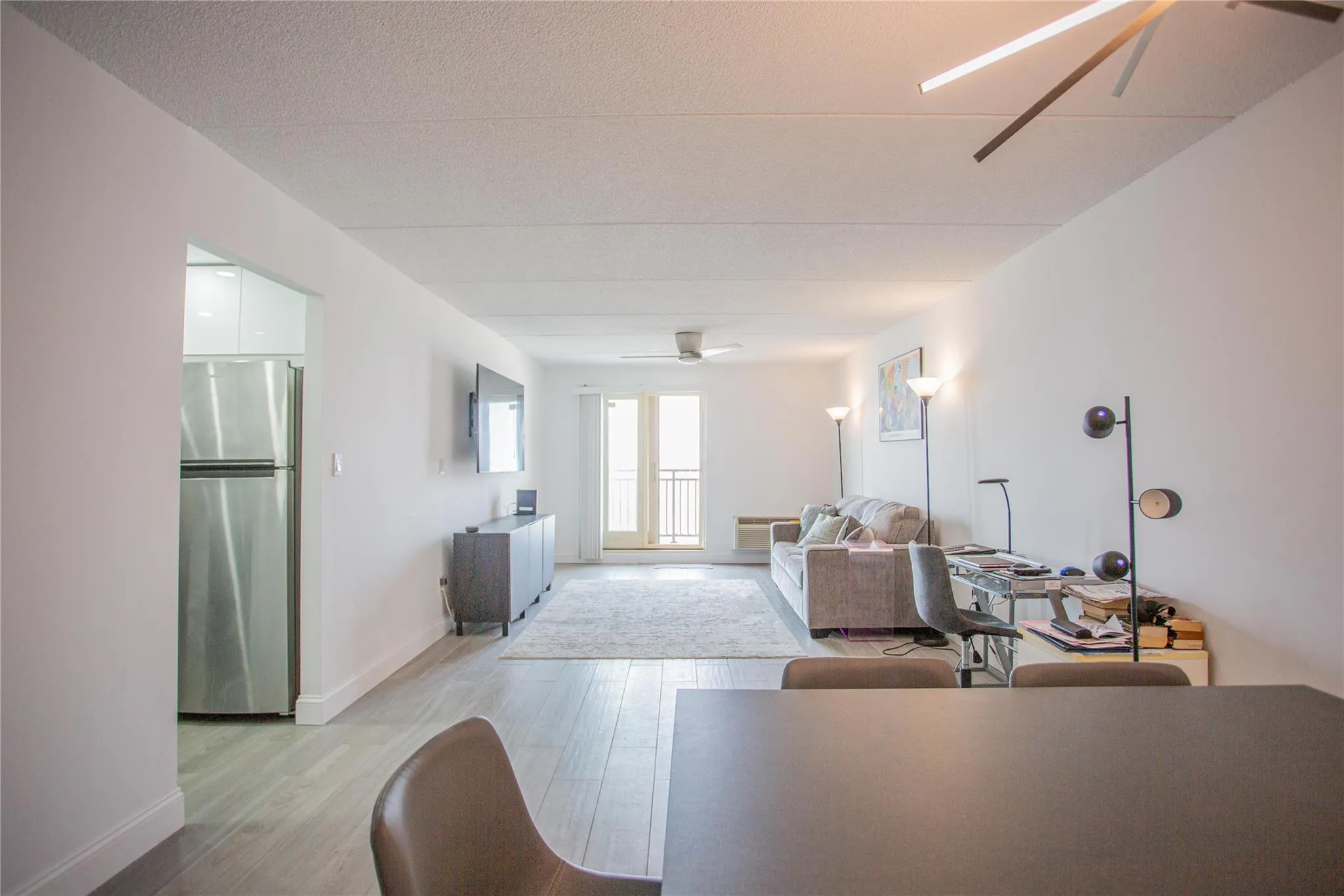 Living room featuring ceiling fan, light wood-style flooring, a textured ceiling, and an office area Living room featuring ceiling fan, light wood-style flooring, a textured ceiling, and an office area