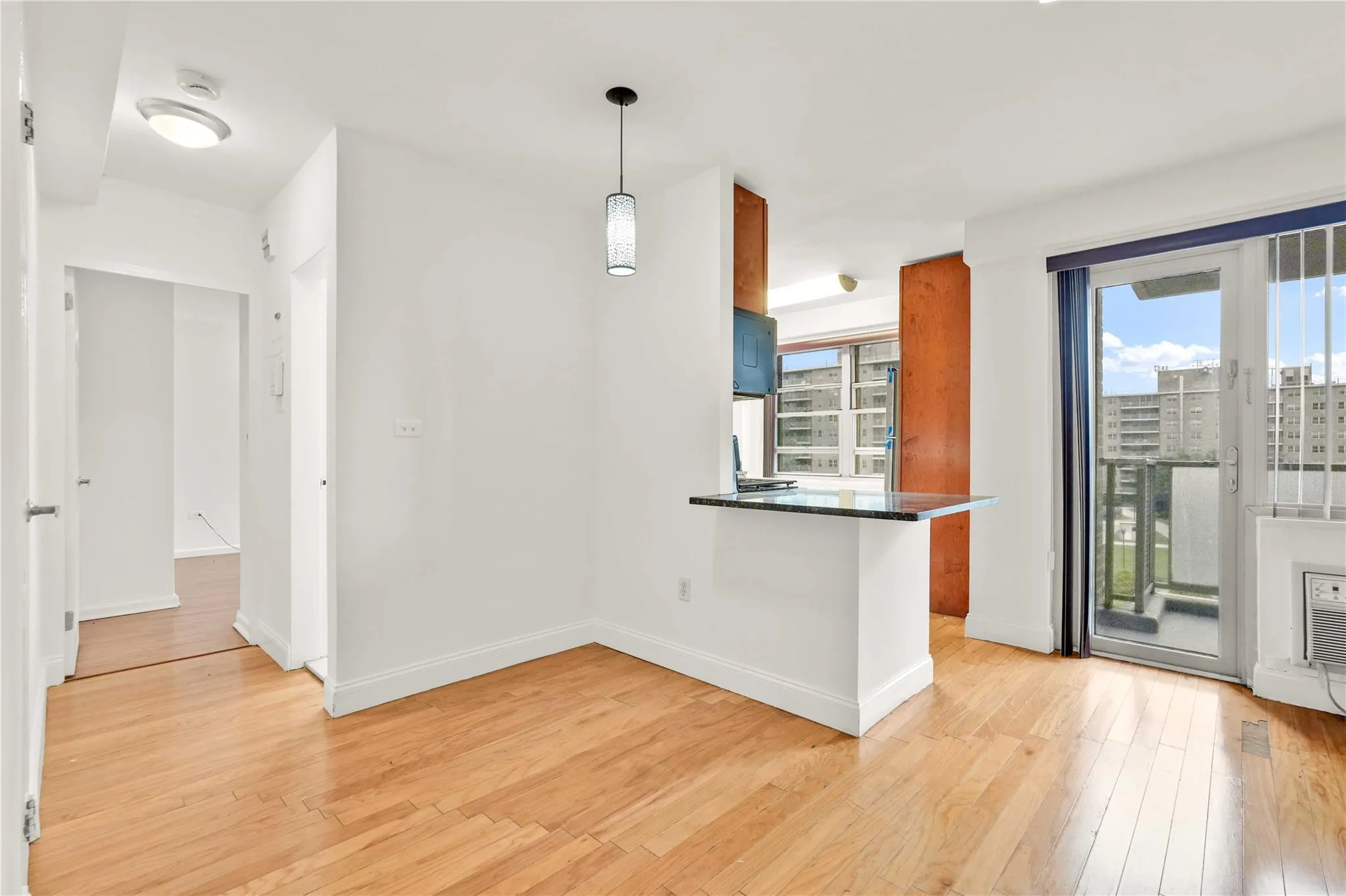 Kitchen with light wood finished floors, dark countertops, a peninsula, and pendant lighting Kitchen with light wood finished floors, dark countertops, a peninsula, and pendant lighting