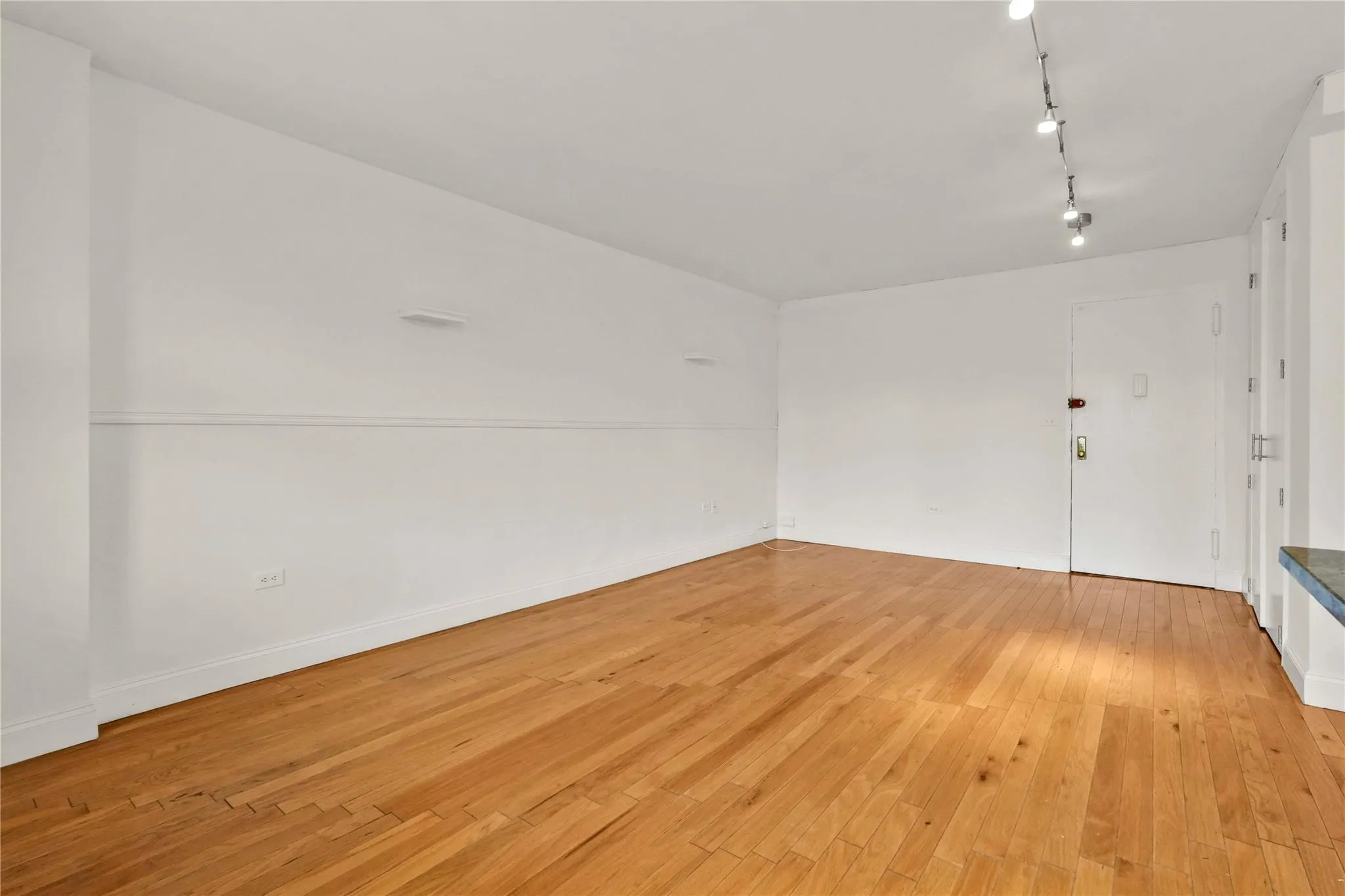 Unfurnished room with light wood-style floors and track lighting Unfurnished room with light wood-style floors and track lighting