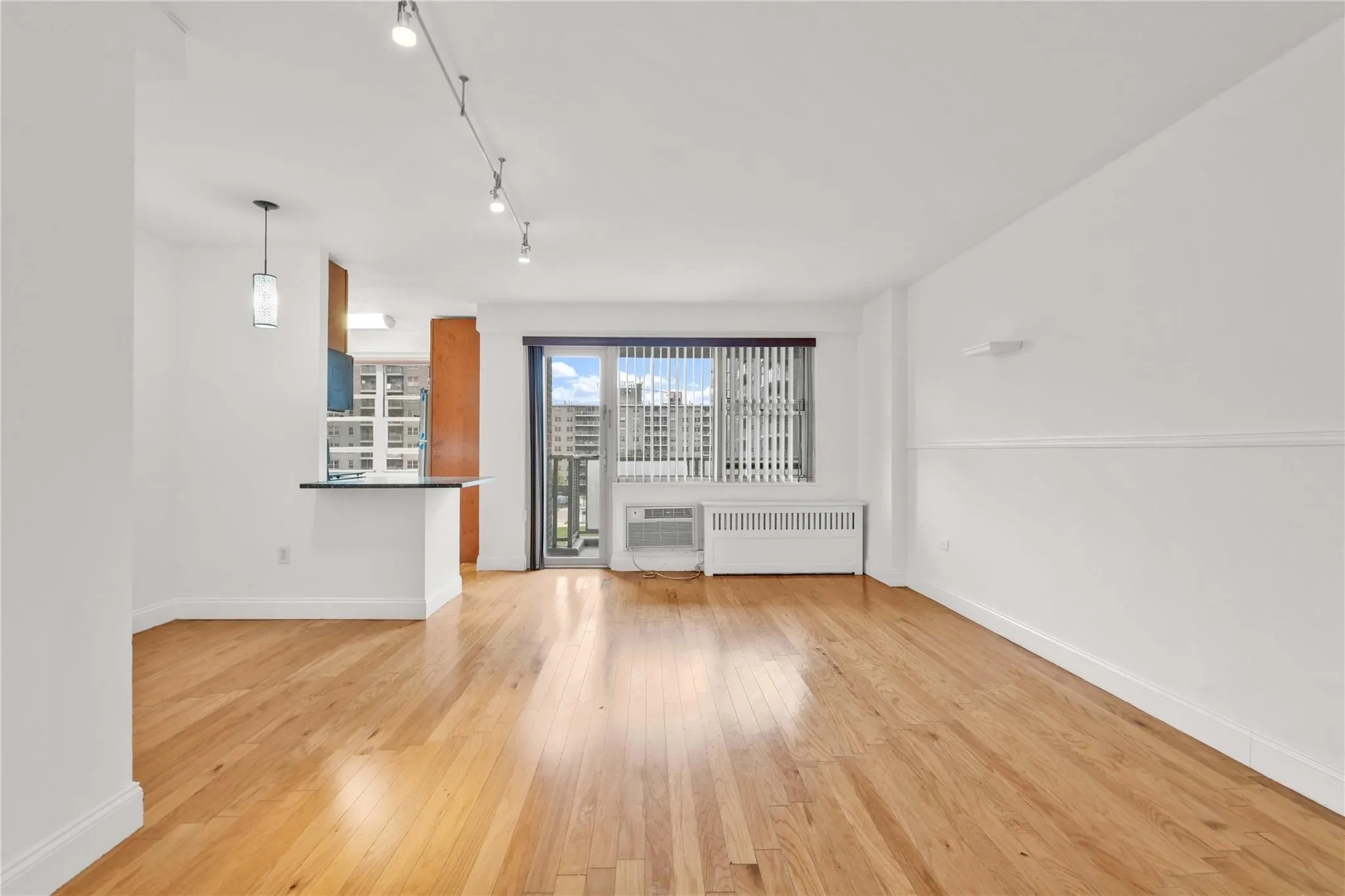Unfurnished living room with track lighting, light wood-type flooring, and radiator Unfurnished living room with track lighting, light wood-type flooring, and radiator