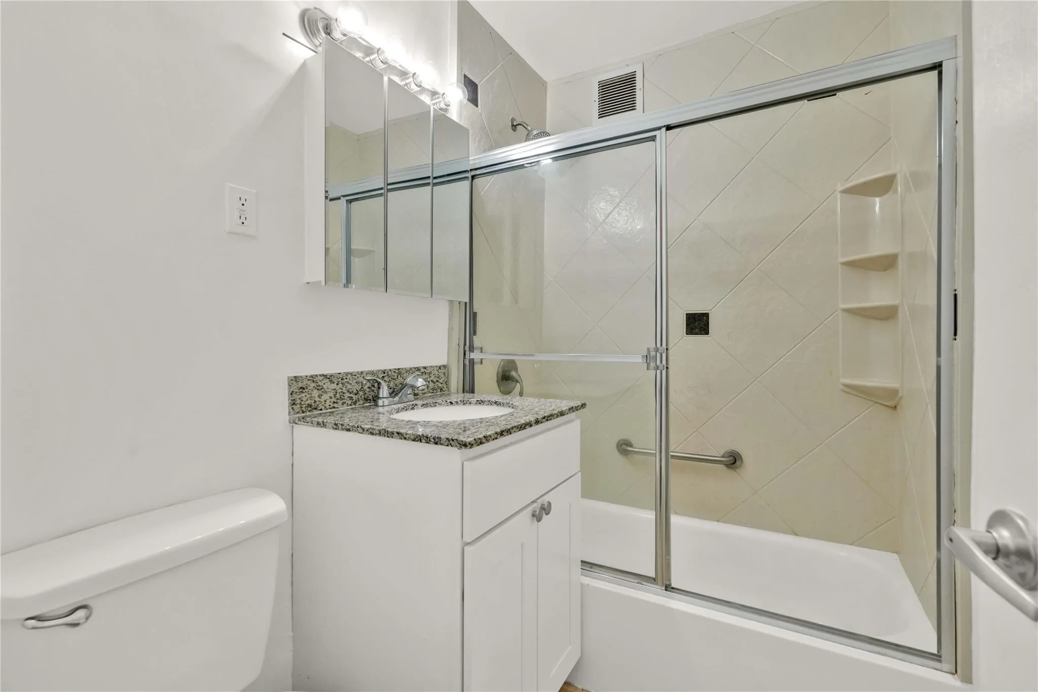 Full bathroom featuring vanity and enclosed tub / shower combo Full bathroom featuring vanity and enclosed tub / shower combo