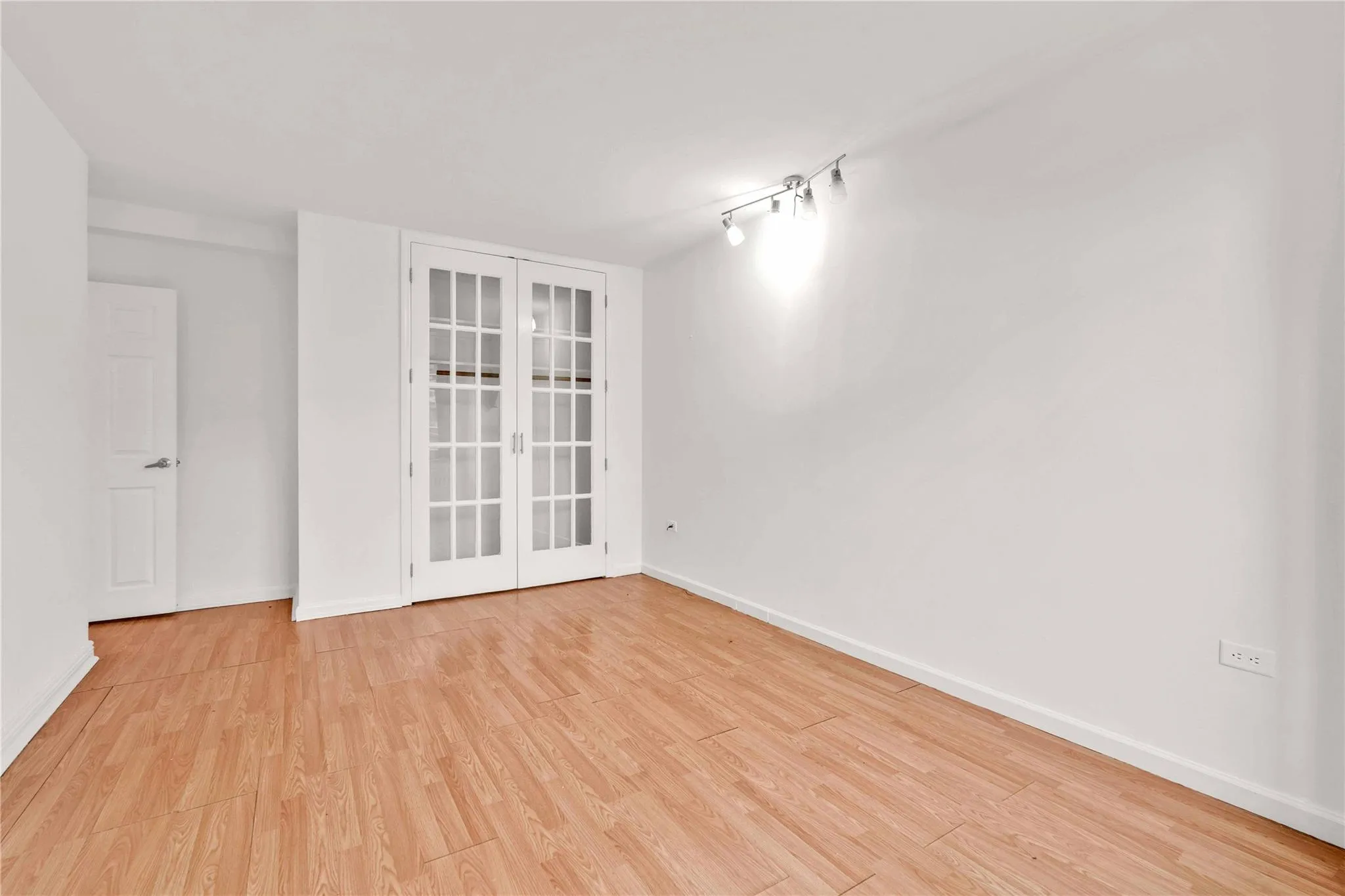 Spare room featuring wood finished floors, french doors, and rail lighting Spare room featuring wood finished floors, french doors, and rail lighting