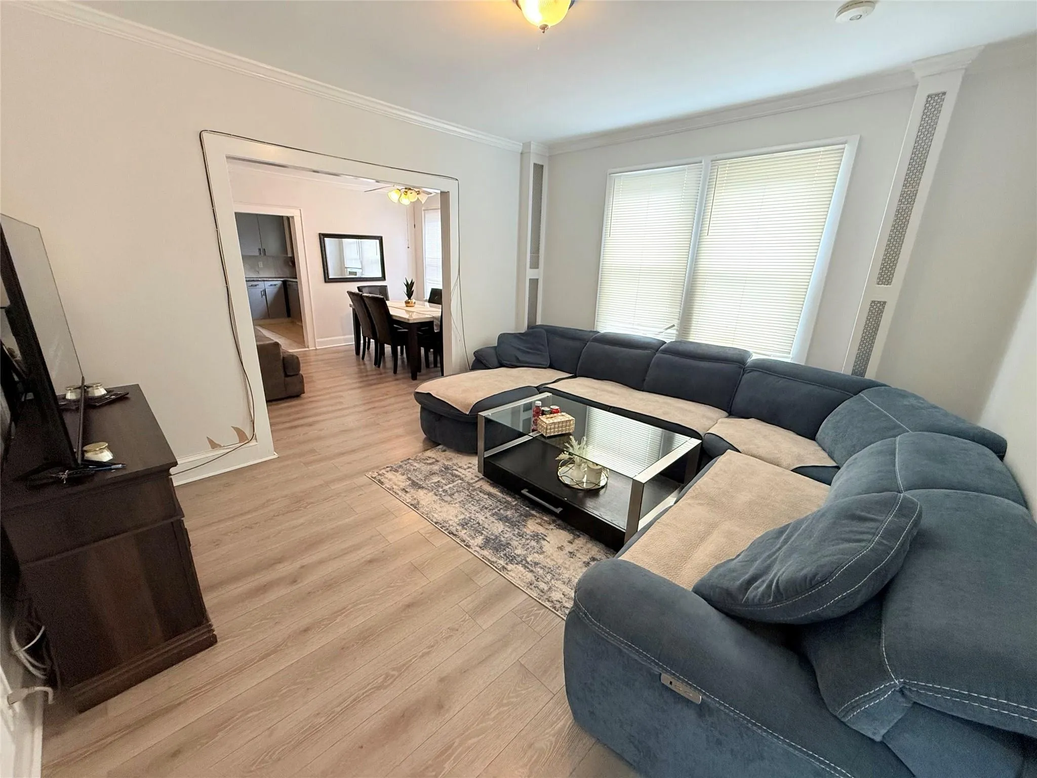 Living area with crown molding, light wood-style flooring, and a ceiling fan Living area with crown molding, light wood-style flooring, and a ceiling fan