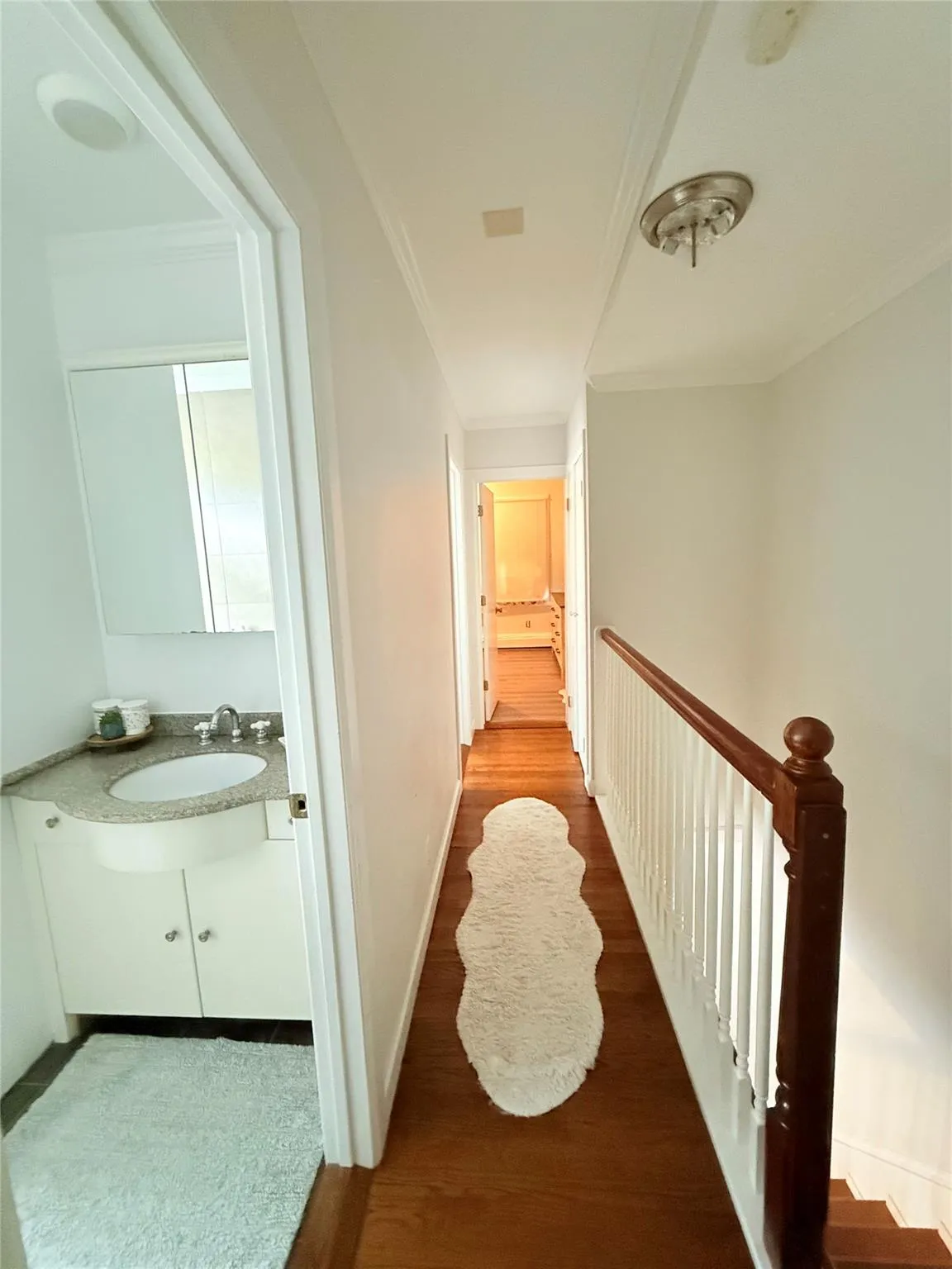 Hallway featuring wood finished floors and ornamental molding Hallway featuring wood finished floors and ornamental molding