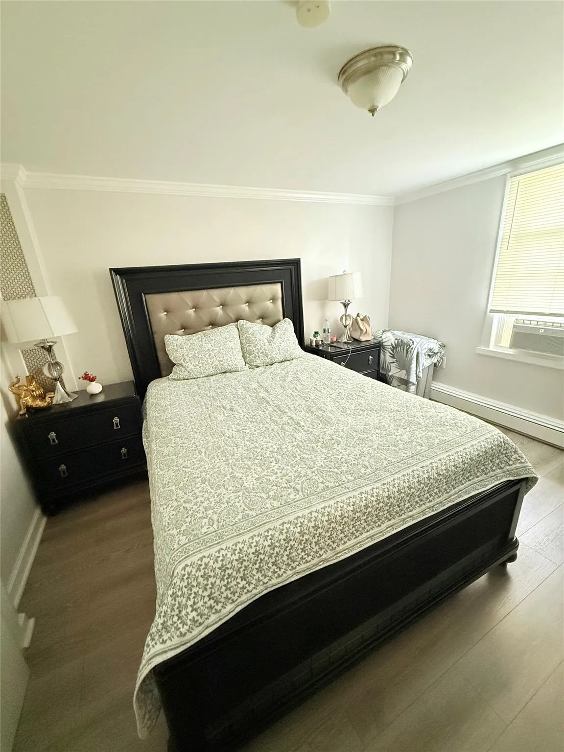 Bedroom with ornamental molding and wood finished floors Bedroom with ornamental molding and wood finished floors