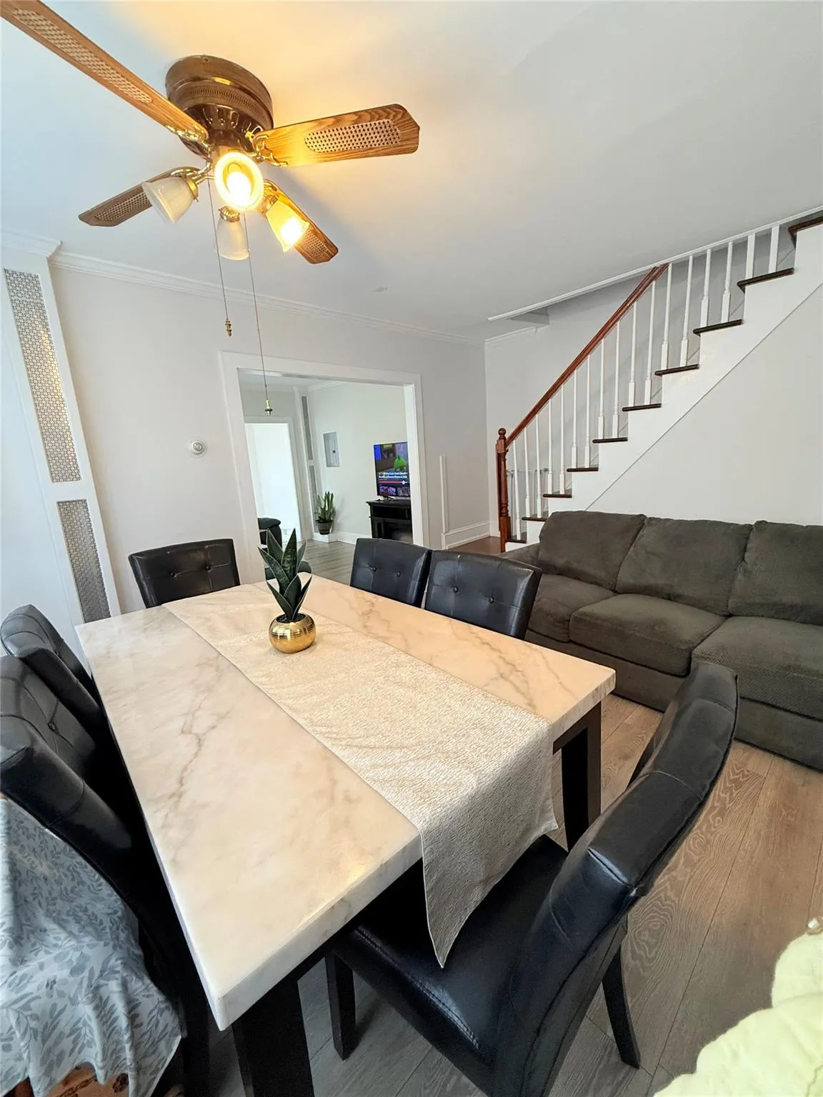 Dining space featuring stairway, wood finished floors, ceiling fan, and ornamental molding Dining space featuring stairway, wood finished floors, ceiling fan, and ornamental molding