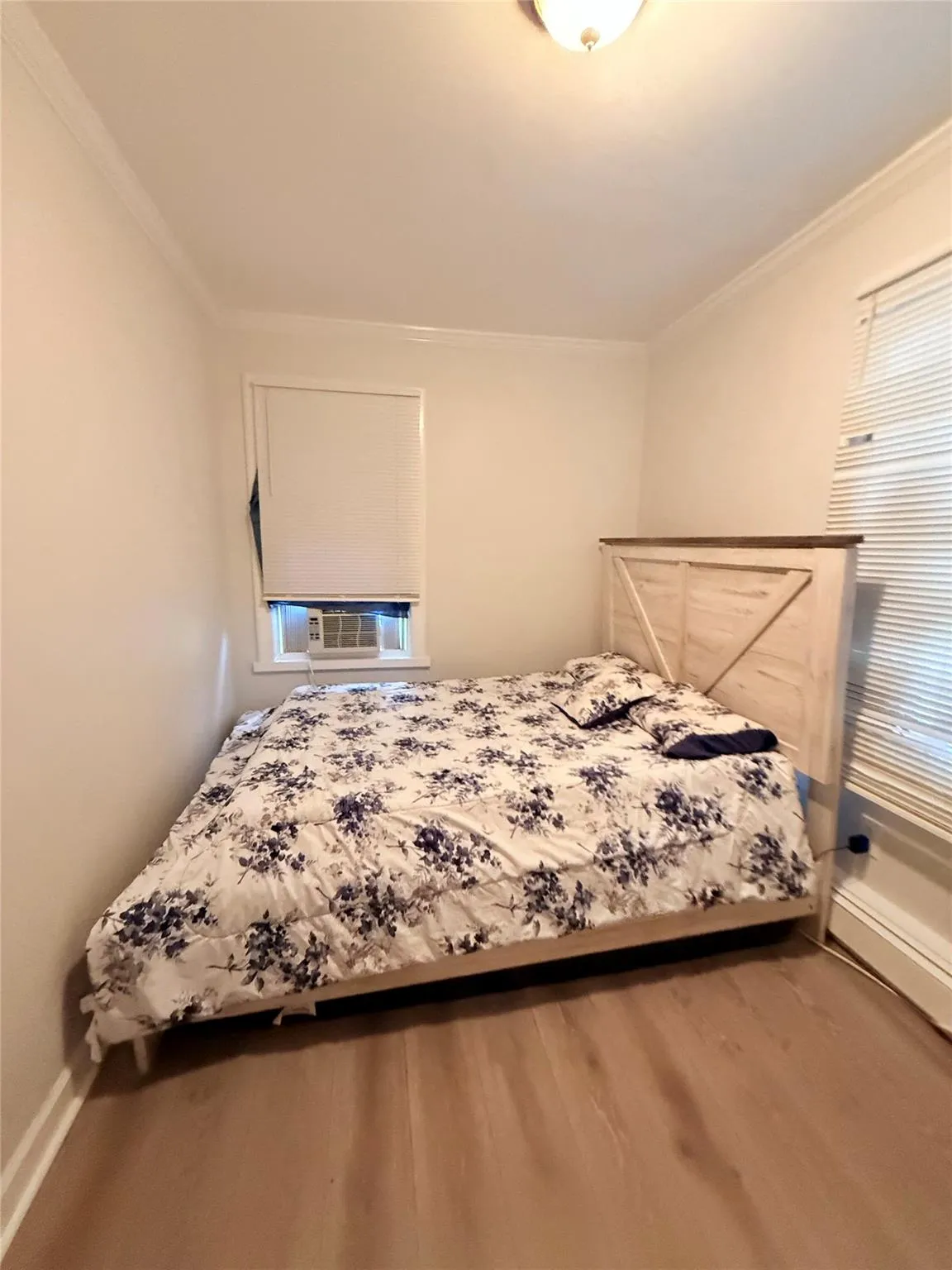 Bedroom featuring crown molding, wood finished floors, and cooling unit Bedroom featuring crown molding, wood finished floors, and cooling unit