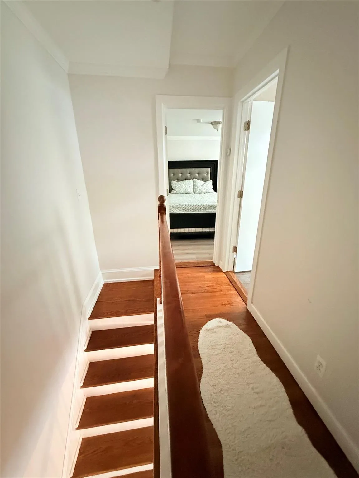 Stairway featuring wood finished floors and crown molding Stairway featuring wood finished floors and crown molding