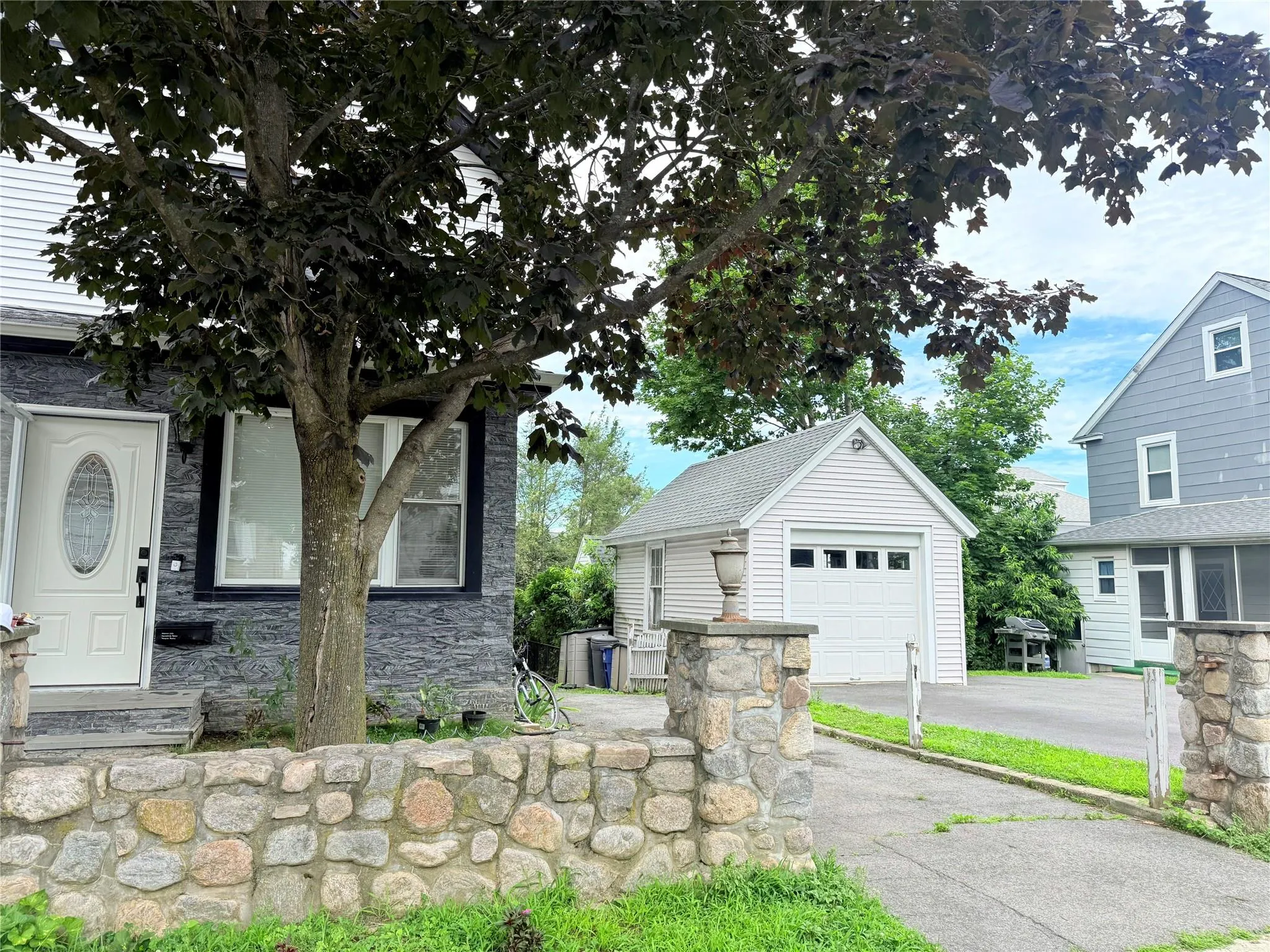 View of front of home featuring an outdoor structure, stone siding, asphalt driveway, and a detached garage View of front of home featuring an outdoor structure, stone siding, asphalt driveway, and a detached garage