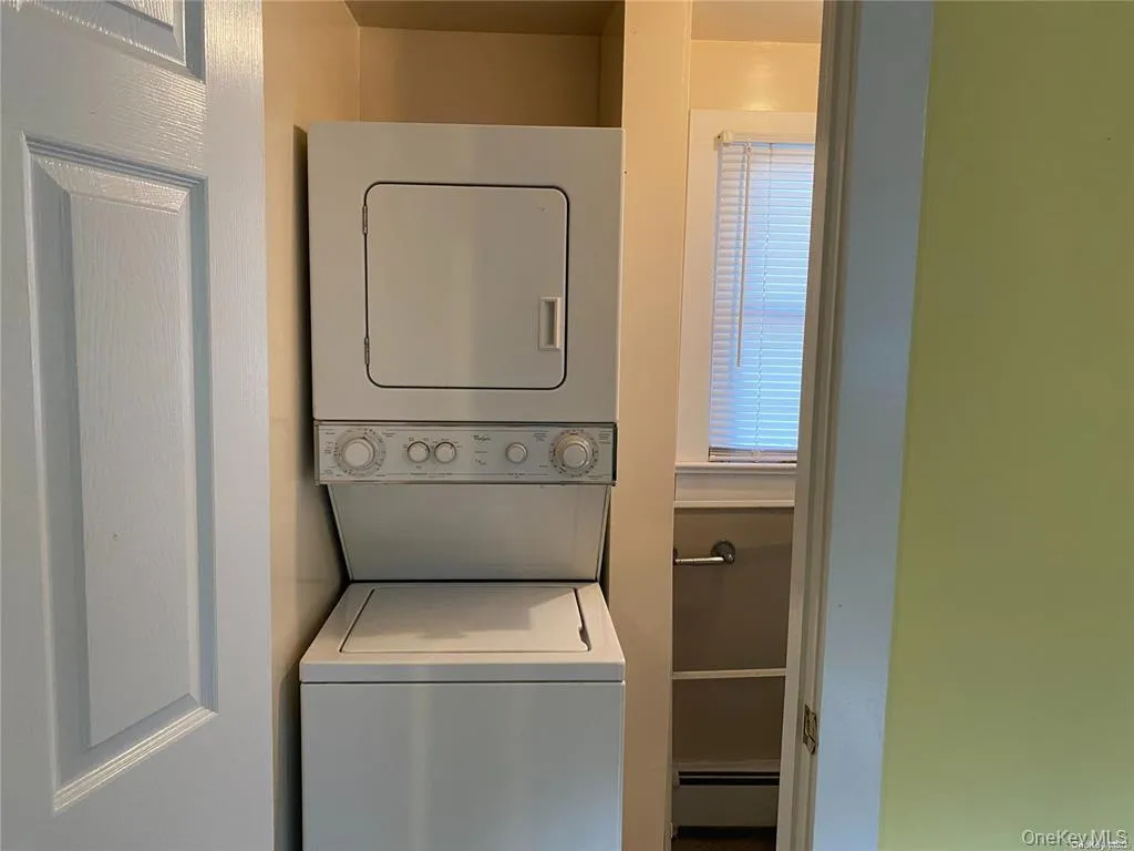 Laundry room featuring estacked washer and dryer and a baseboard heating unit Laundry room featuring estacked washer and dryer and a baseboard heating unit