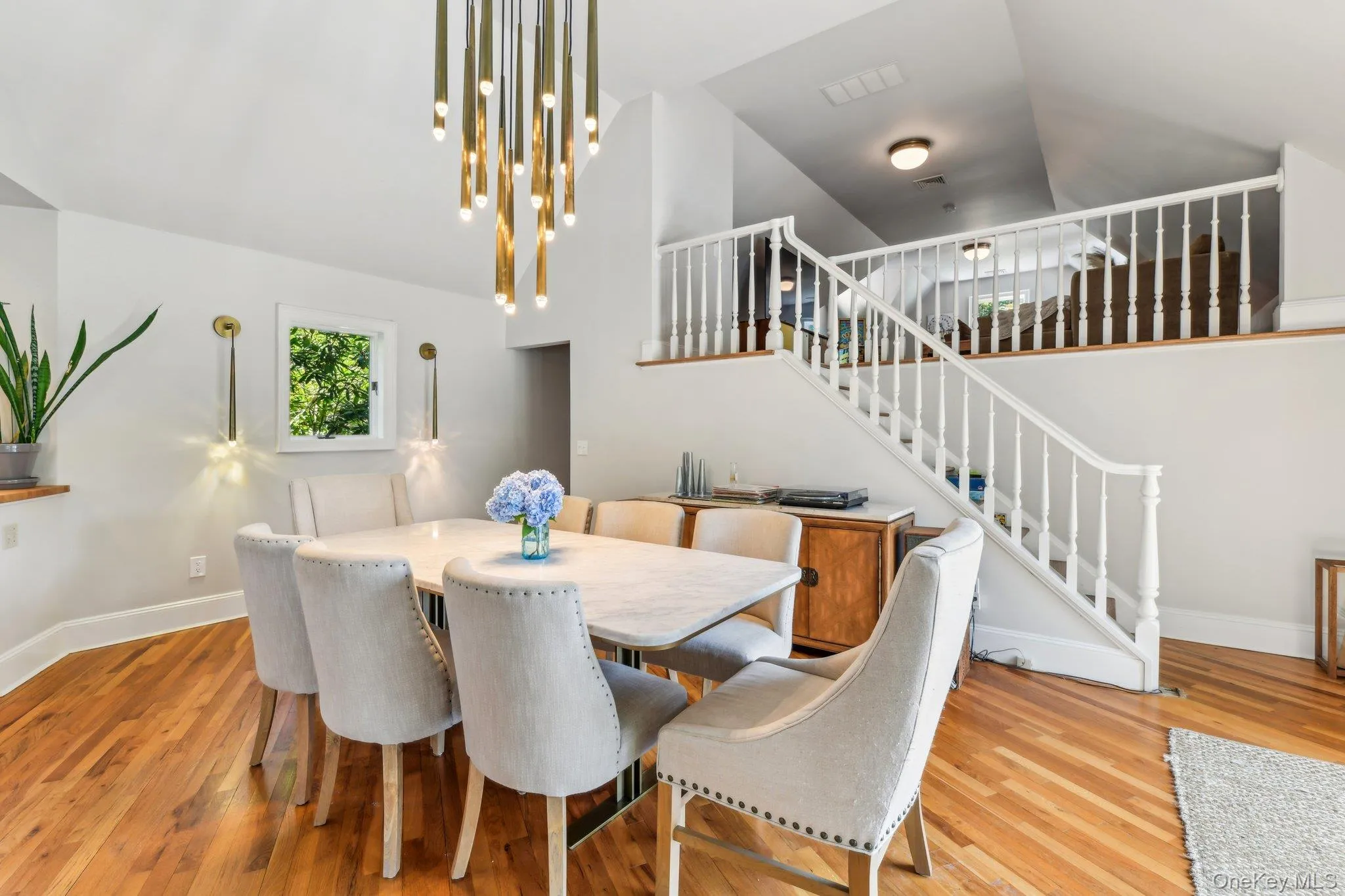 Dining space with wood finished floors, lofted ceiling, and stairs Dining space with wood finished floors, lofted ceiling, and stairs