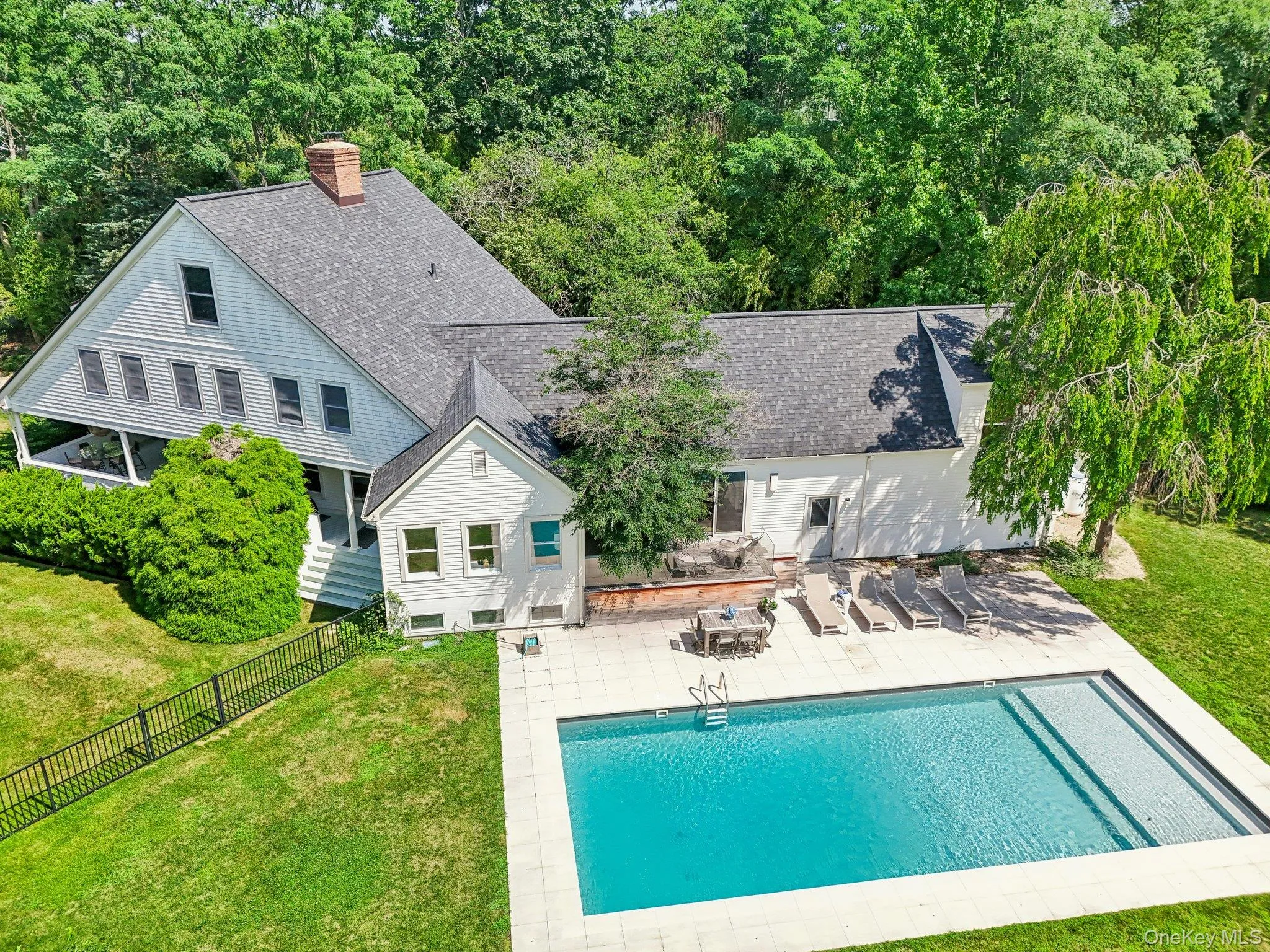 Back of property with roof with shingles, a patio area, a fenced backyard, a chimney, and a forest view Back of property with roof with shingles, a patio area, a fenced backyard, a chimney, and a forest view