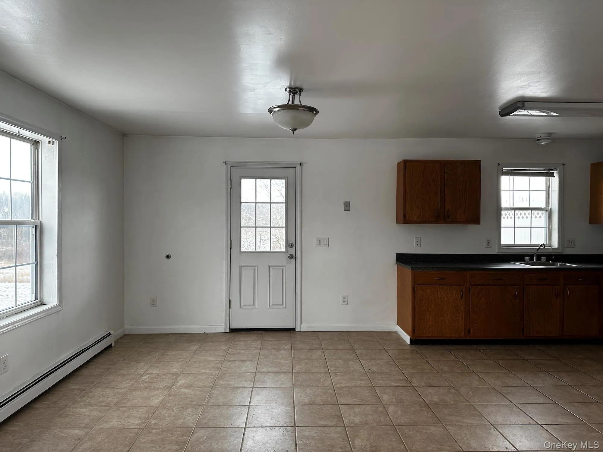 Kitchen with dark countertops, a baseboard radiator, and light tile patterned floors Kitchen with dark countertops, a baseboard radiator, and light tile patterned floors