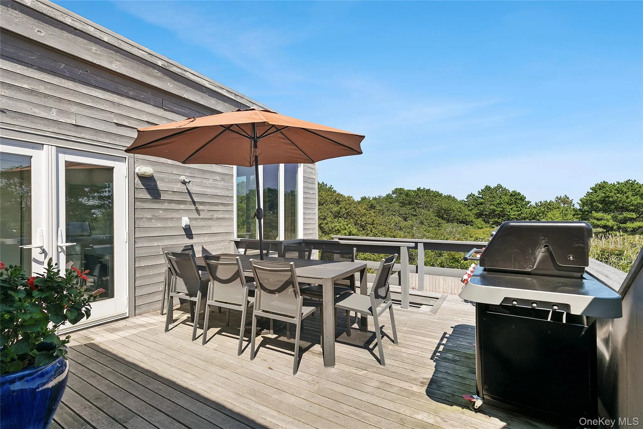 Deck with outdoor dining area, a grill, and view of wooded area Deck with outdoor dining area, a grill, and view of wooded area