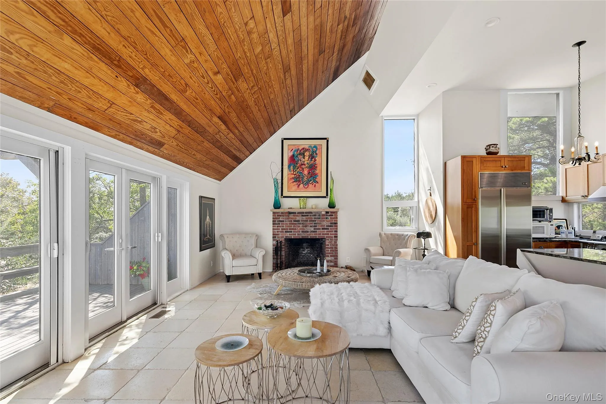 Living area with wooden ceiling, light tile patterned floors, high vaulted ceiling, a fireplace, and a chandelier Living area with wooden ceiling, light tile patterned floors, high vaulted ceiling, a fireplace, and a chandelier