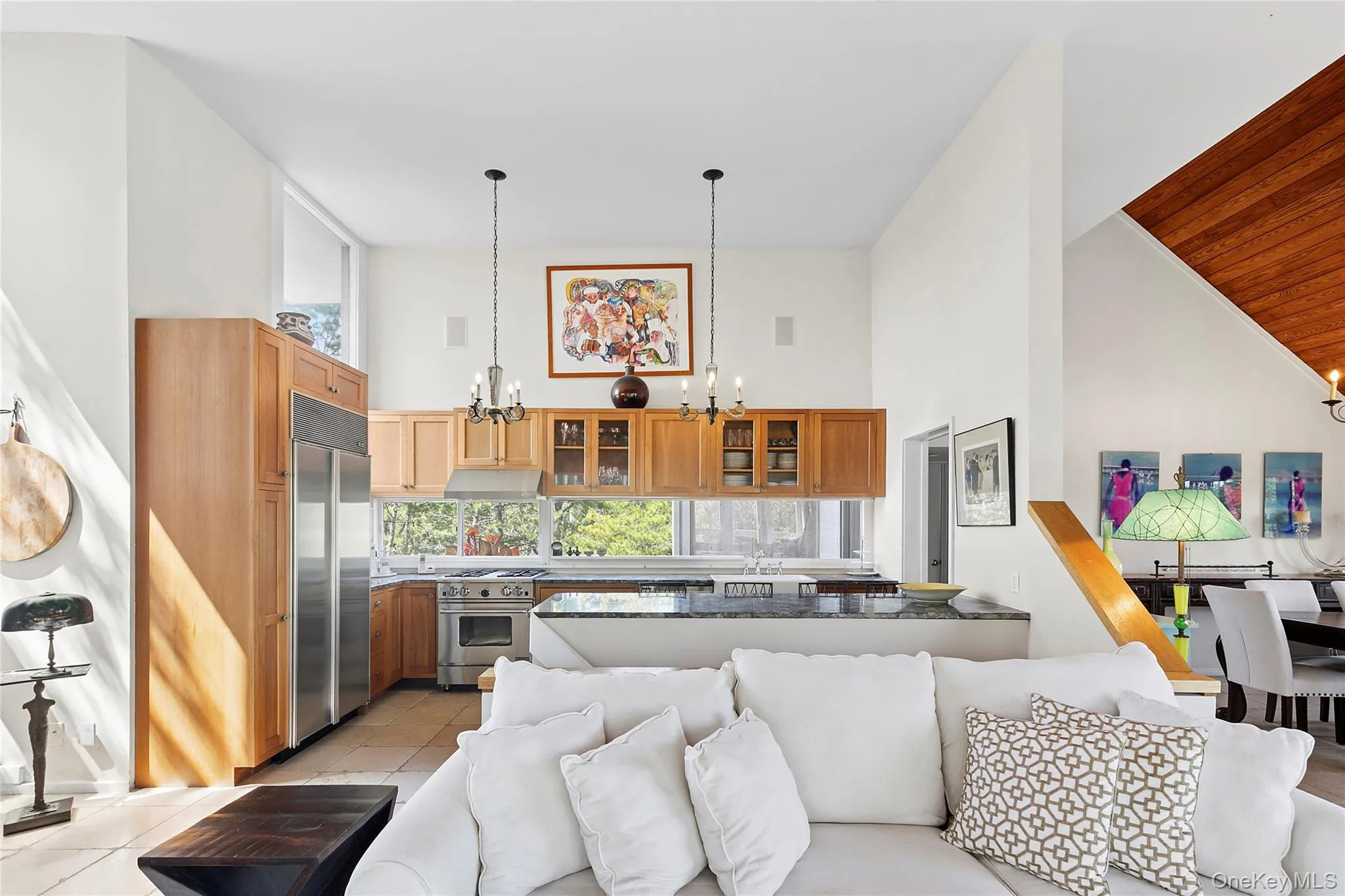 Kitchen with high vaulted ceiling, a chandelier, glass insert cabinets, high end appliances, and light tile patterned floors Kitchen with high vaulted ceiling, a chandelier, glass insert cabinets, high end appliances, and light tile patterned floors